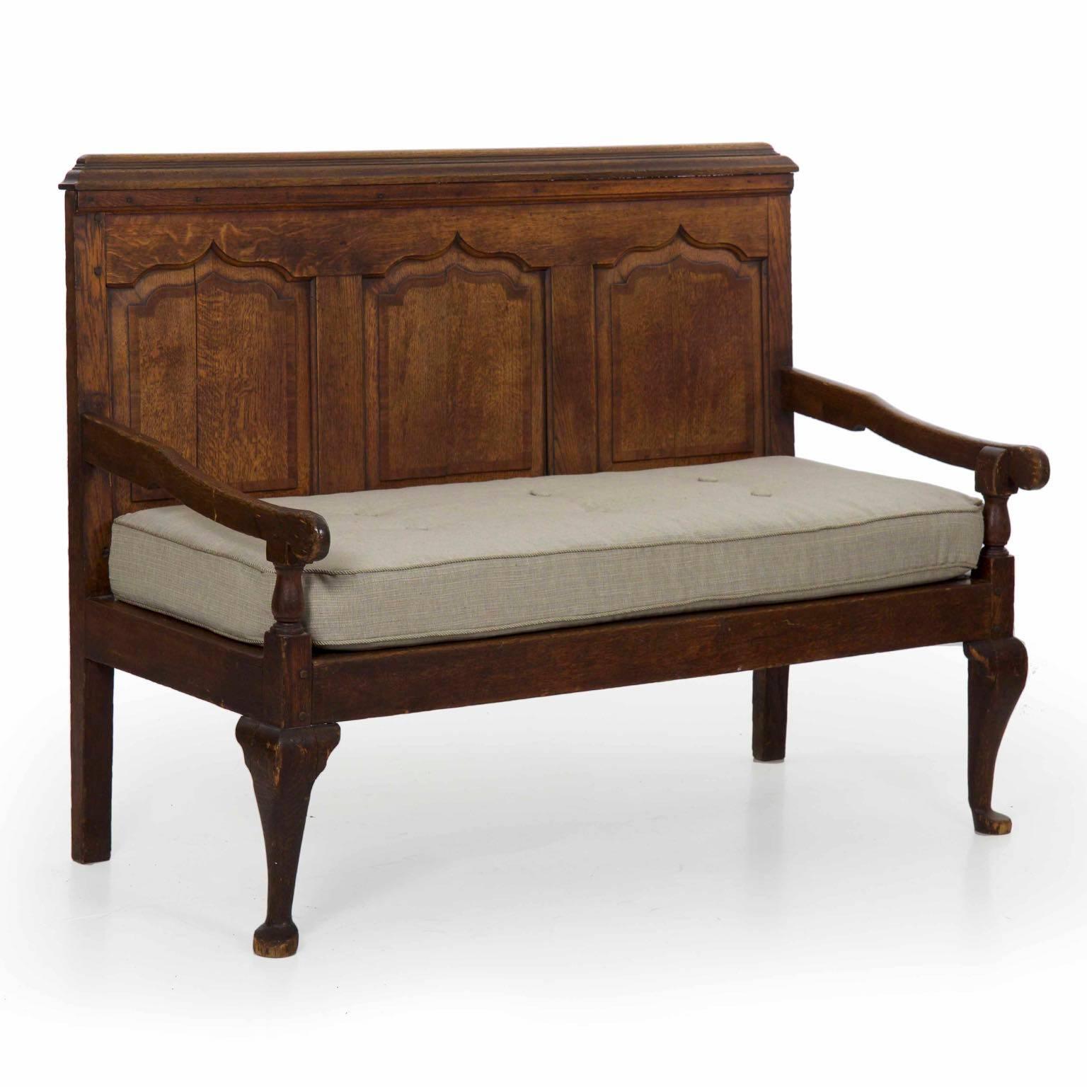 A gorgeous worn antique English hall settle, this antique wooden bench is beautifully formed with arched recessed oak panels in the Gothic taste. The tenon-mortise construction brings strength and longevity to the form, the thick and generous solid