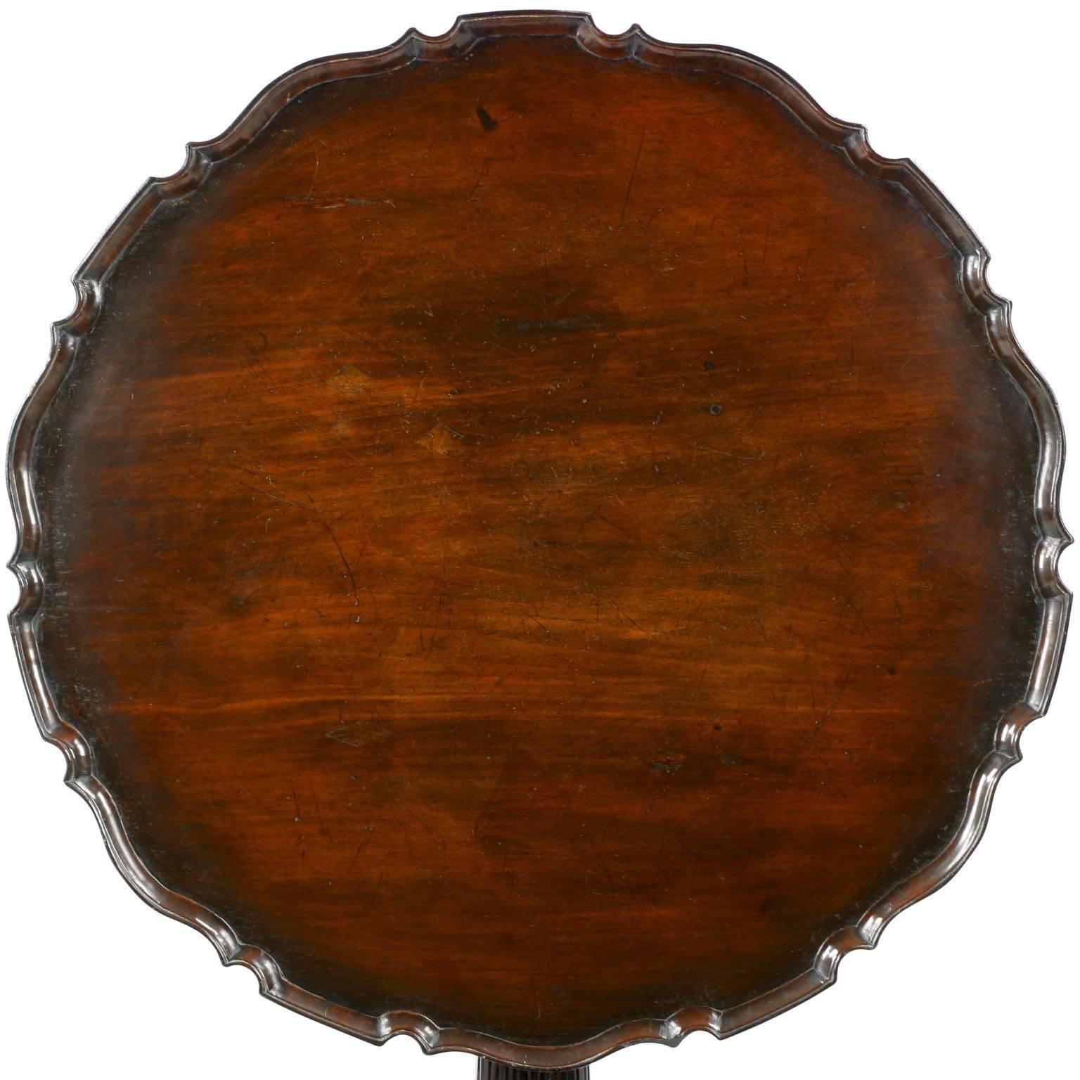A profusely and handsomely carved piece, this beautiful George III tea table is highly developed and most striking.  The pie crust is painstakingly formed by first affixing to a lathe, carefully turning until the rim becomes raised, scroll cutting