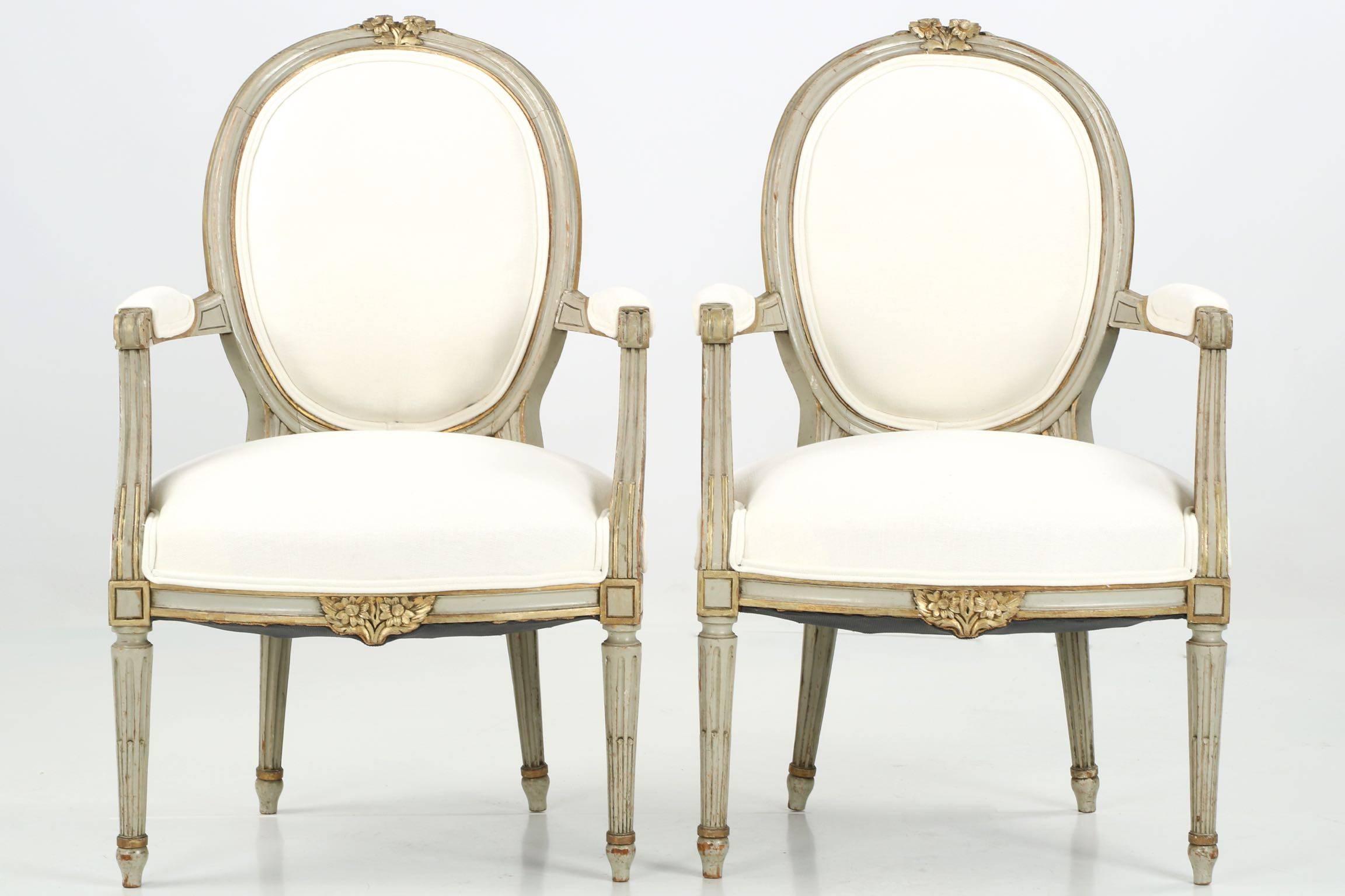This very attractive pair of French fauteuils from the first half of the 20th Century retains an early and well worn painted surface with gilded highlights.  The simple molded frames are embellished with floral carvings in the crest and apron, both