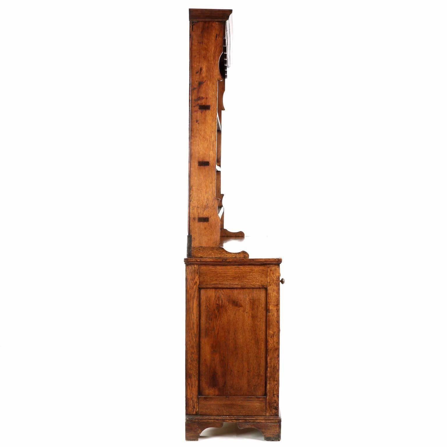 A gorgeous and early cupboard, probably crafted in England during the late 18th to early 19th century, this fine case piece remains in a very good condition with a deeply patinated golden oak surface throughout.  It is a two piece cupboard, allowing