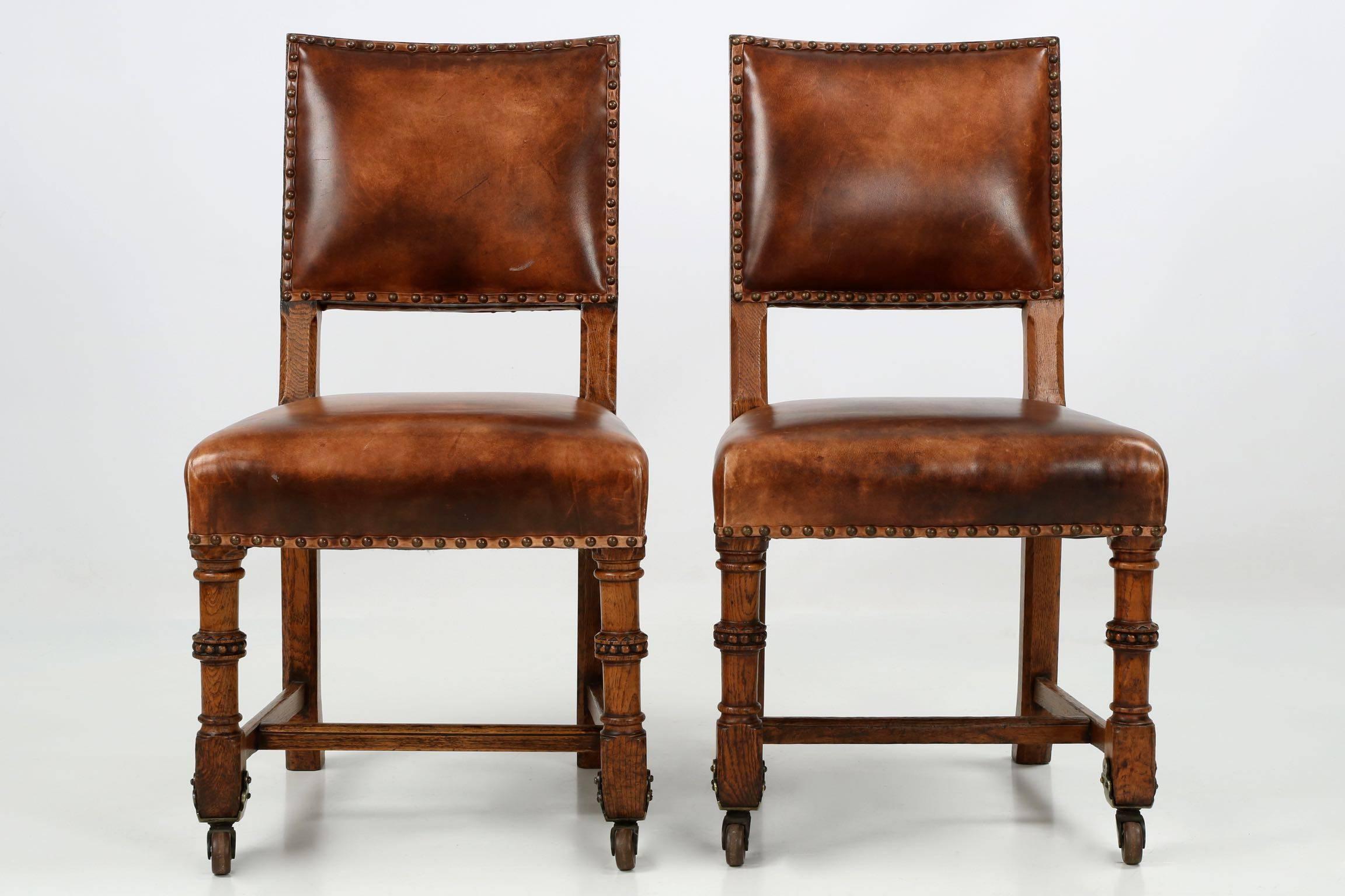 Most attractive and pleasant, this gorgeous pair of early 20th century leather upholstered side chairs exhibit the nostalgia of a smoky study or library. They are masculine and bold forms that exhibit strength in all components of the design - the