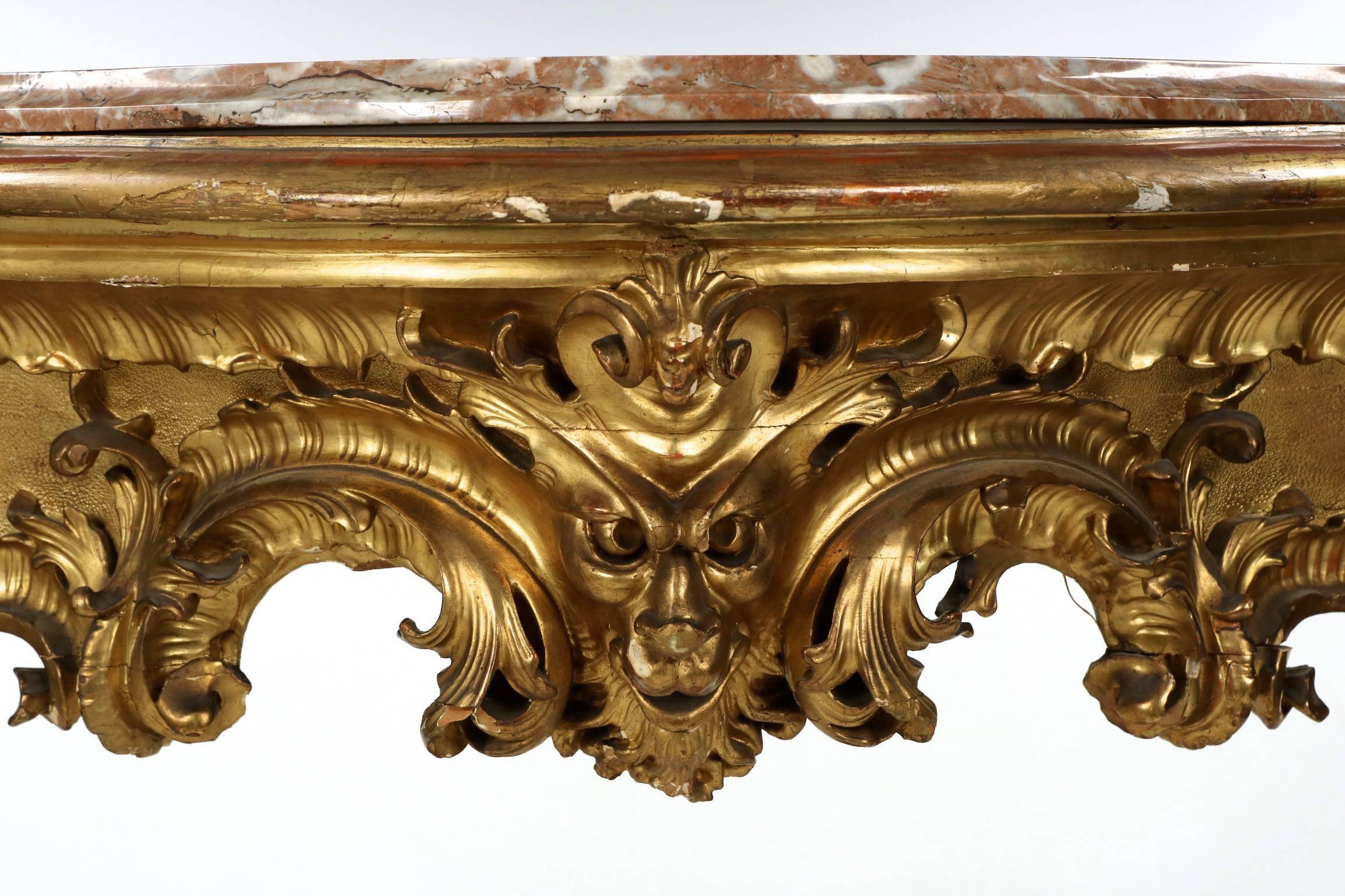 A most vigorous and fluid work from the third quarter of the 19th century, this gorgeous carved giltwood console table is most heavily embellished in the distinctive Louis XV taste, employing the luxurious excesses of Rococo to it’s fullest over