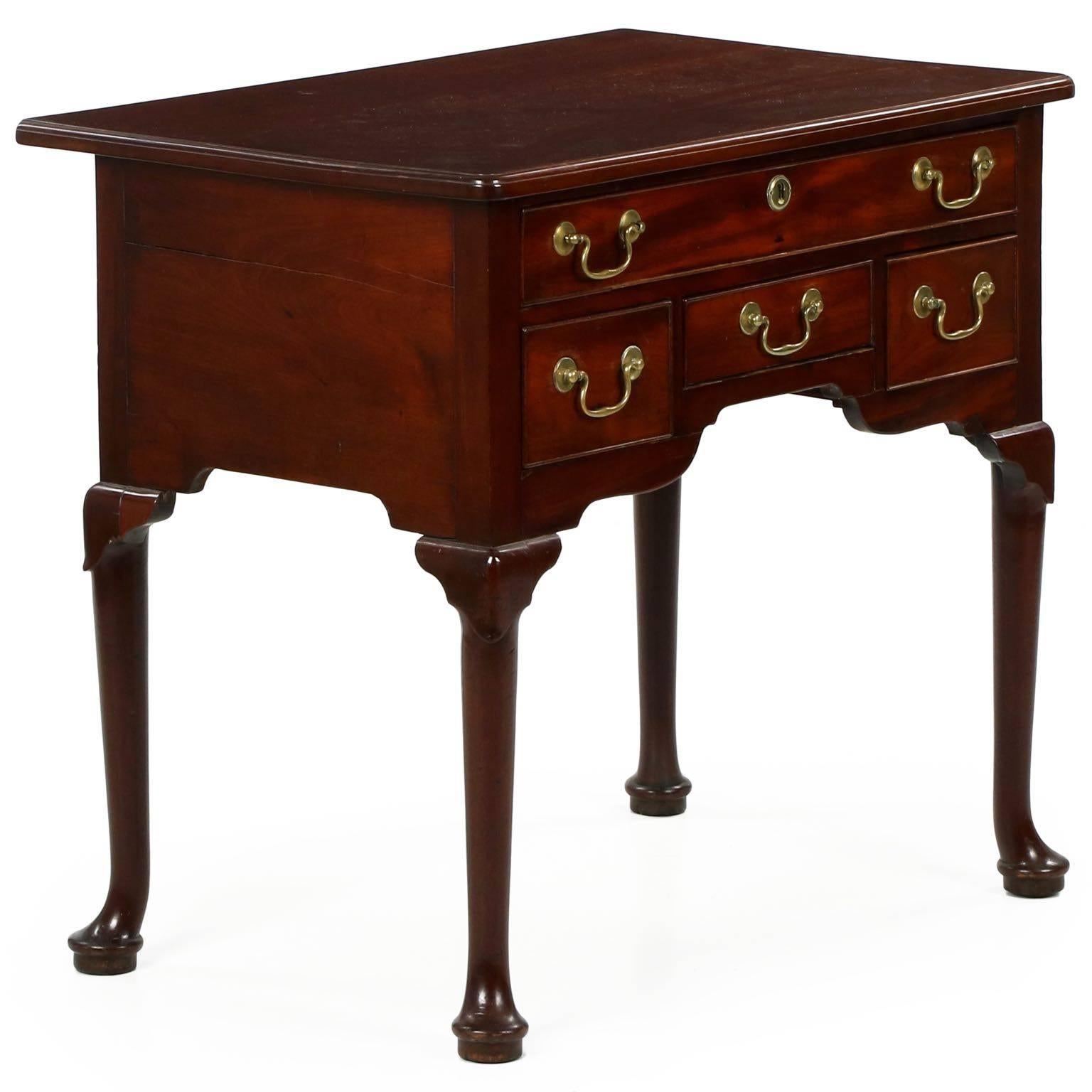 The warm red surface of this gorgeous mahogany lowboy is well preserved with a deep glowing patina throughout from years of rubbed wear. The top is a single solid plank of mahogany affixed to the case with a series of small triangular pine blocks