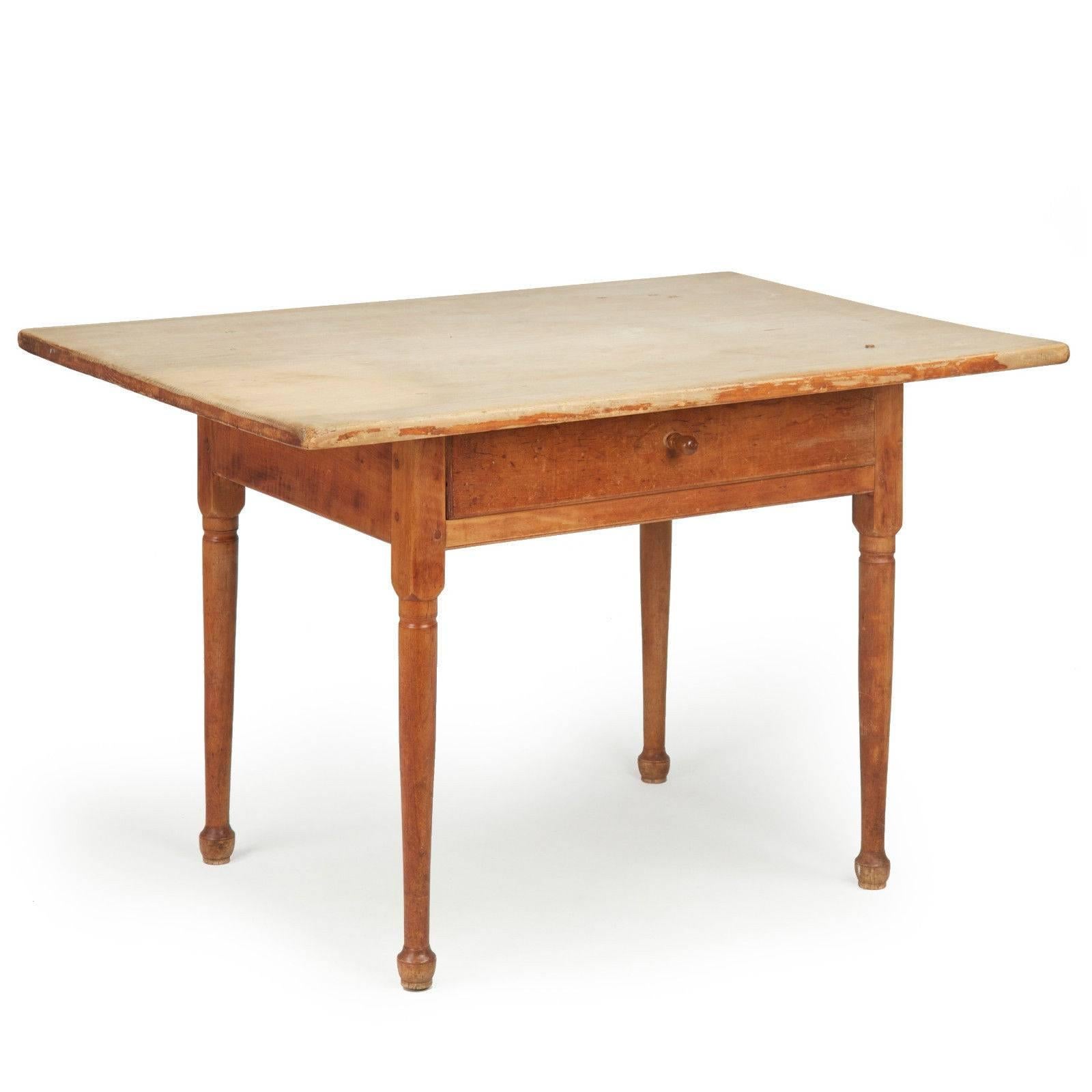 A most attractive primitive table, the table is austere and free of embellishment, a piece intended for function and use in a rural home. The top is a gorgeous and incredibly broad single solid plank of white pine, affixed at each corner with large