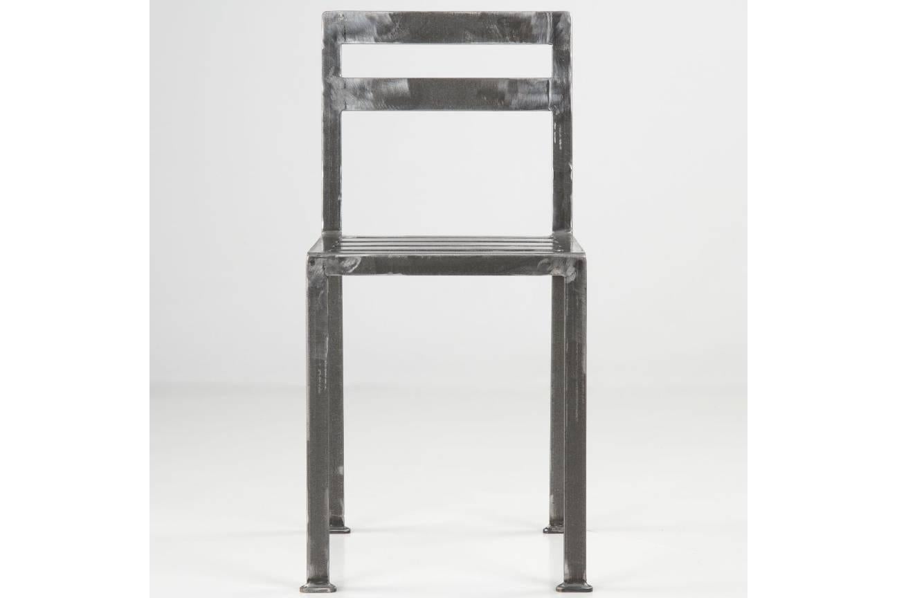 With angular and stoic architectural lines, this chair is a Minimalist piece absolutely free of embellishment. The raw carbon steel is beautifully finished in a low-gloss lacquer, but in such a way that the rough handcrafted nature of the piece is