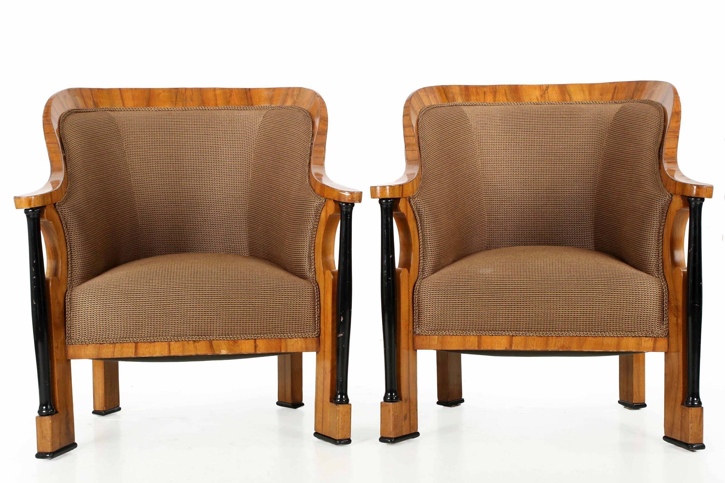 This exceptional pair of Biedermeier tub chairs make an incredibly powerful presentation with their unique and robust form. The exaggerated hoop of the back is faceted in a complex manner that allows the flat of the arm to taper into a sharp edge