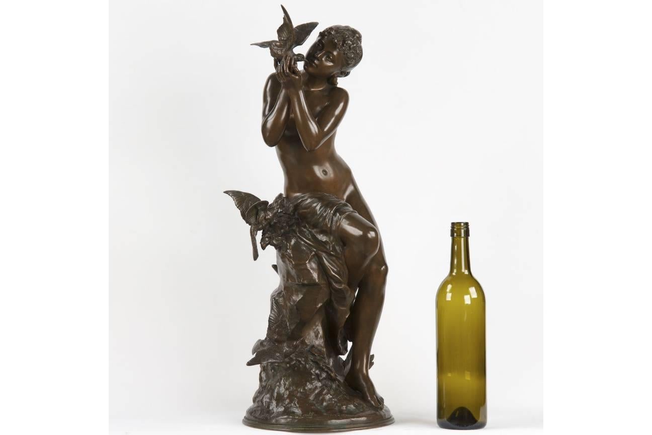 A work that captures the very essence of the Art Nouveau spirit, this excellent model by Mathurin Moreau depicts a young maiden seated on a rock with a bird in hand while two other birds fly about beneath her. She appears almost to be in