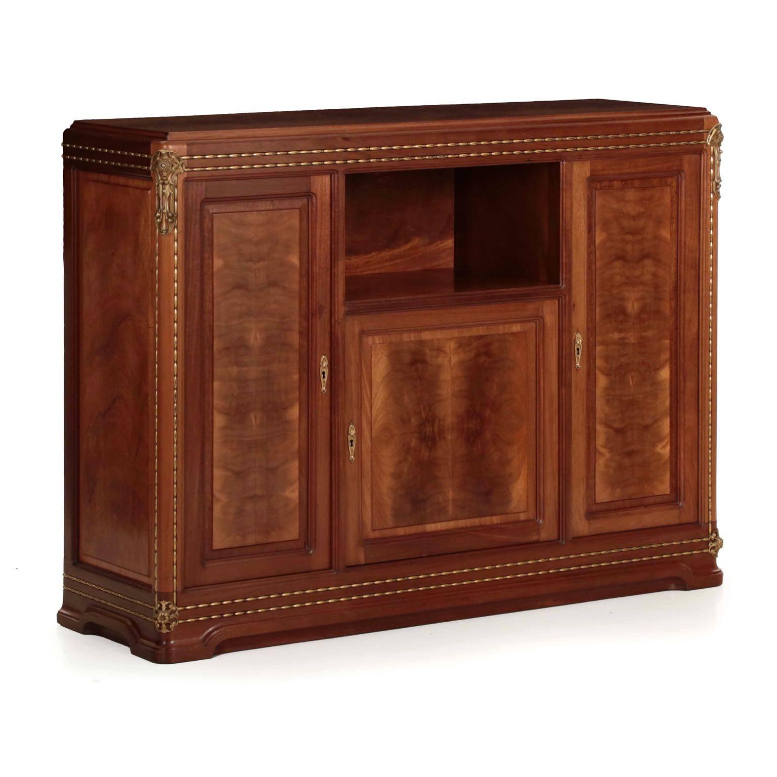 This is an inordinately well crafted piece of furniture. Thick and generous selections of mahogany are carved into organic molded forms inset with a turned ball-and-barrel brass beading that is inordinately crisp and fine. Custom bronze mounts on