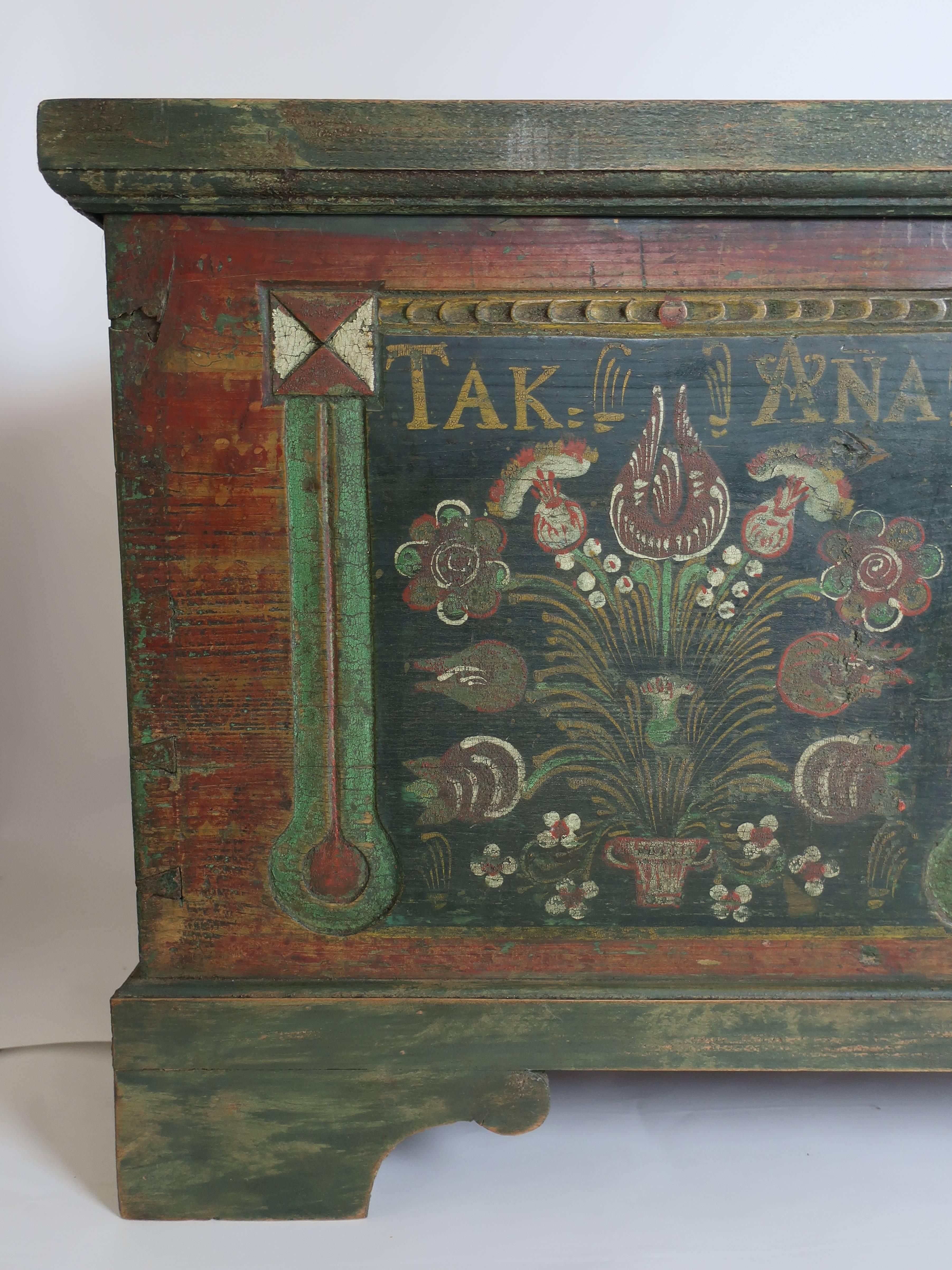Polychrome blanket chest inscribed, Kat and Ana, Anno, 1848. Green and red base with polychrome figures of tulips, white flowers and simple columns defining the tombstone panels. There is some decorative carved detail on the front. The chest has