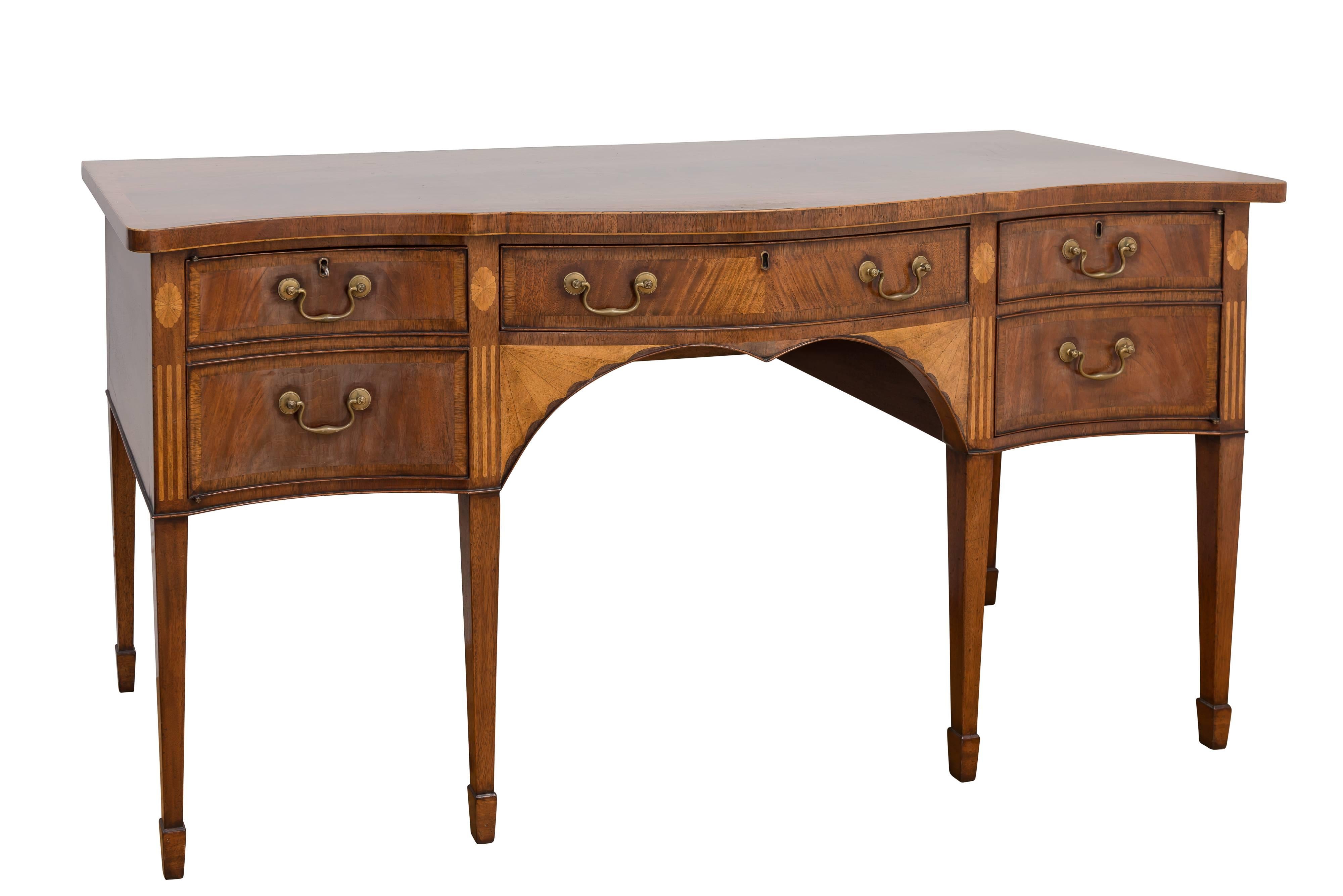 This fine reproduction mahogany sideboard has a serpentine top with inlay edge detail. The sideboard has one center drawer and two concave doors that have crossbanding on perimeter borders. The front has inlay rosette and channel detail on tapered