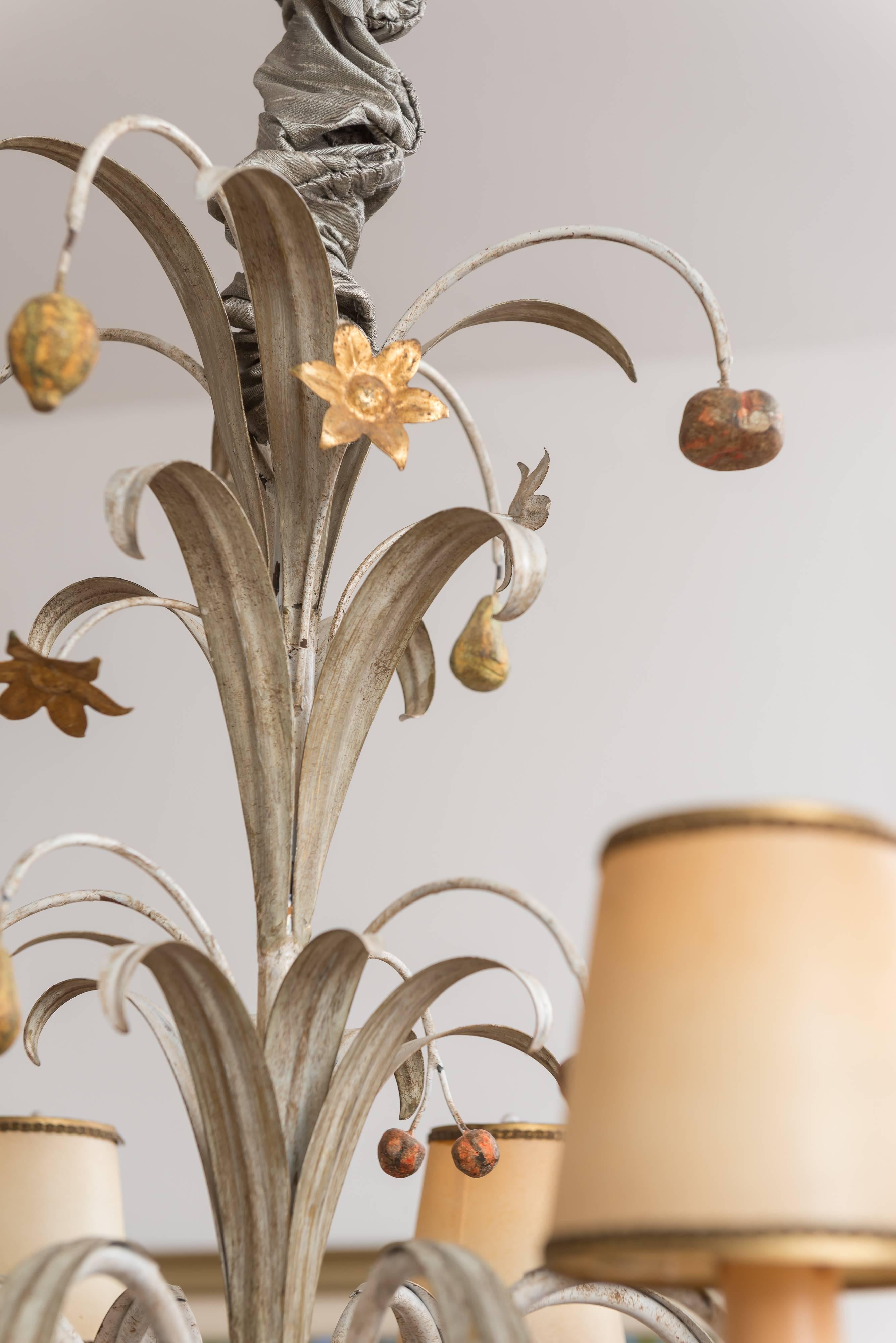 Eight-light Venetian chandelier with hand-carved wood candle cups with acanthus leaves and ball detail. The ornately carved center column has fruit and floral arrangement in an urn with decorative finial. The fixture has a two-tier spray decoration