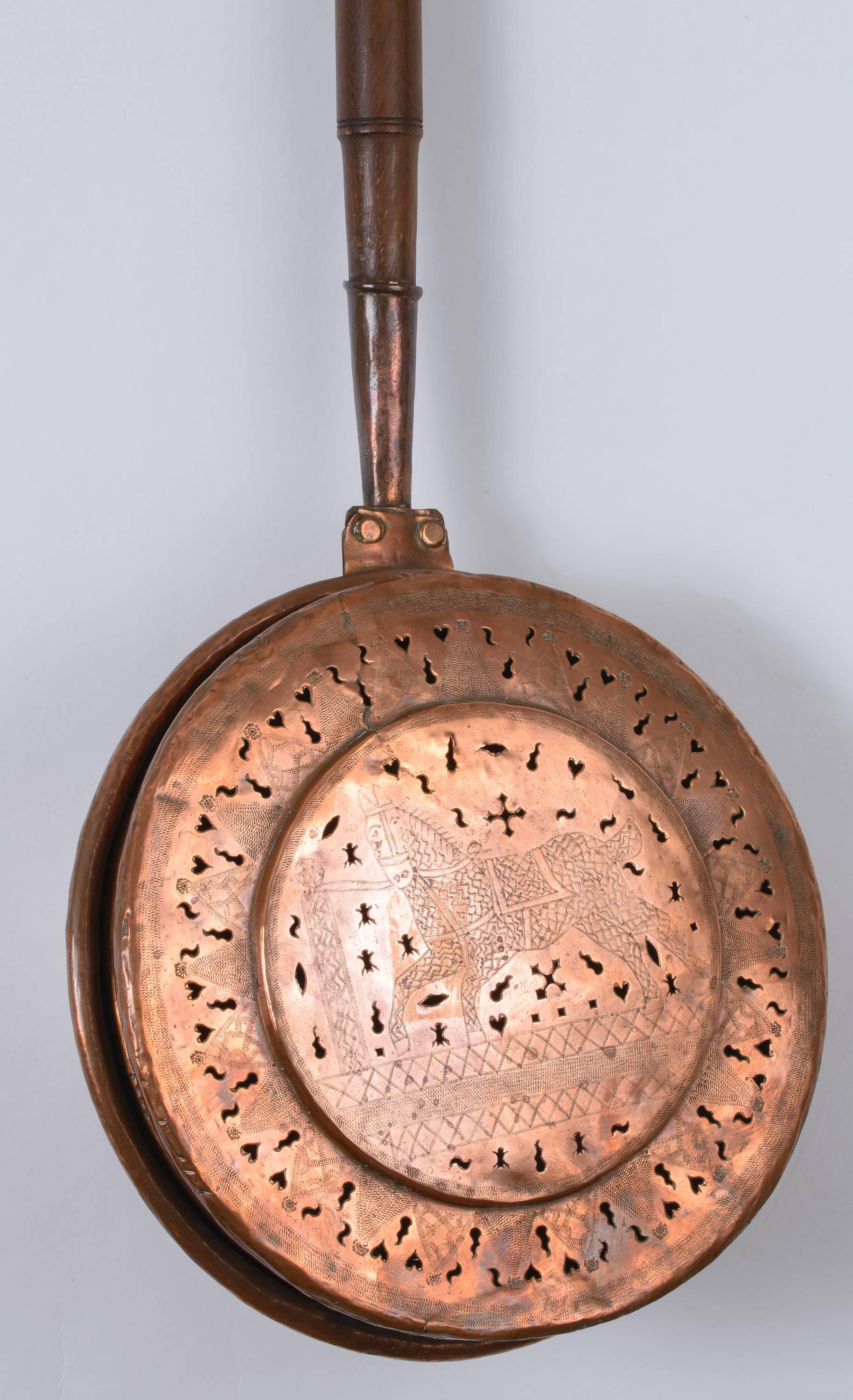 Copper pan is hand-hammered and hand tooled. On the center of the pan is a tethered horse with saddle. The tooling around the recessed edge is of continuous diamond shapes each with its individually tooled pattern. The overall perforations decorate