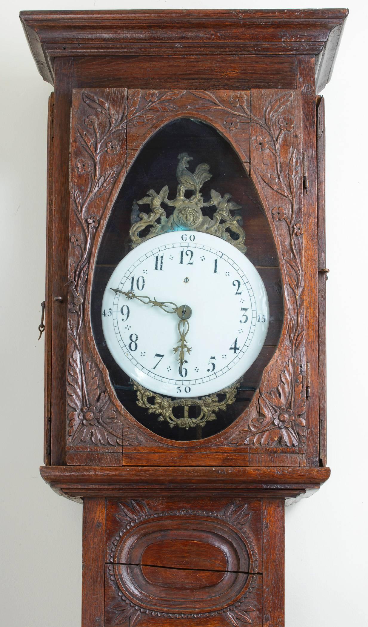 The oak case is heavily carved with edelweiss flowers, branches and berries.  The enamel clock face is hand-painted and indicates the hours, minutes and quarter hour. 
The clock face surround has a wonderful crowing rooster atop, joined with birds