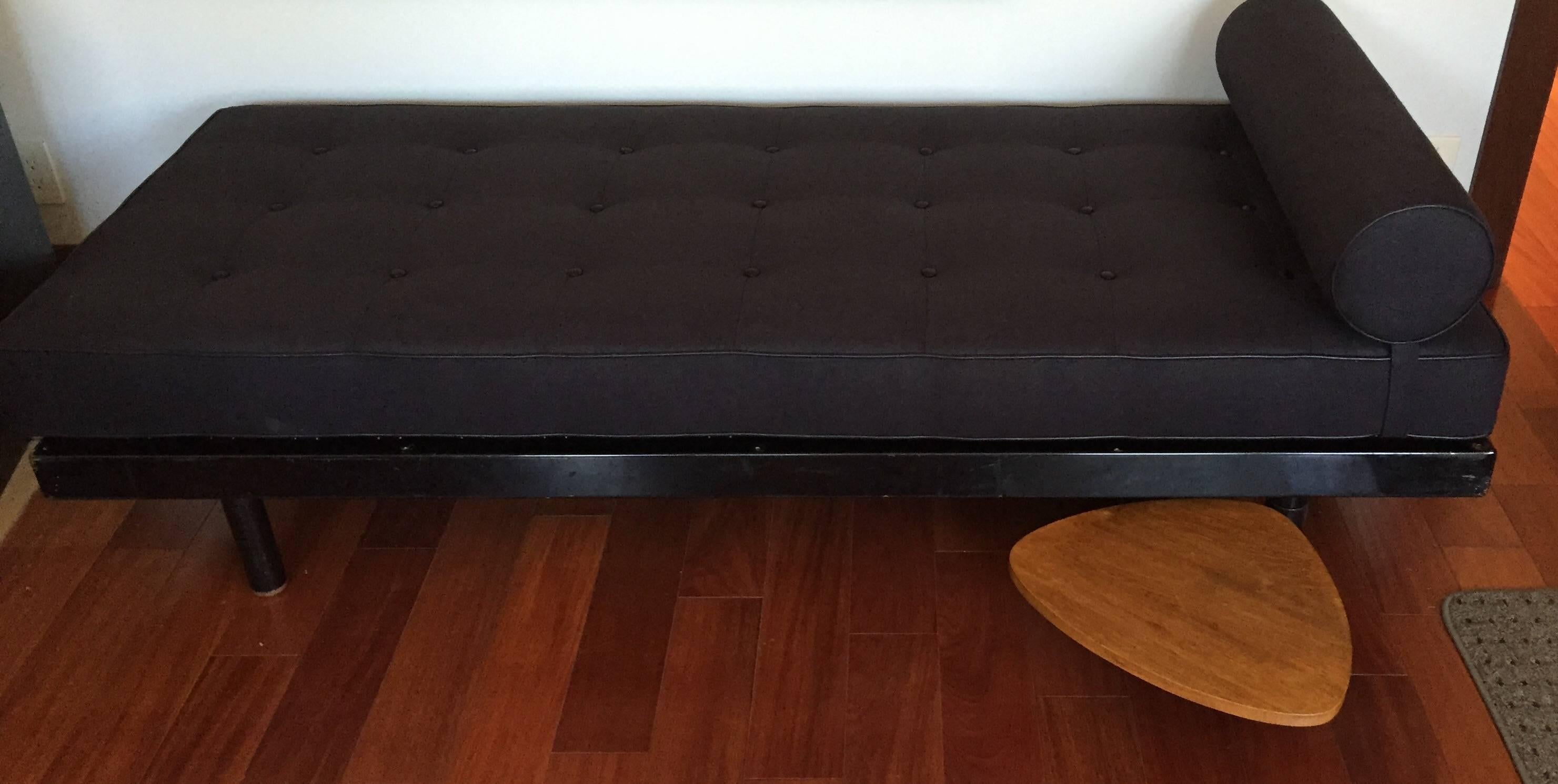 S.C.A.L. daybed by Jean Prouve, circa 1952.
Black enameled bed frame, with a swivel elm shelf by Charlotte Perriand. Mattress is upholstered in black linen with leather trim and buttons. 
Excellent vintage condition.