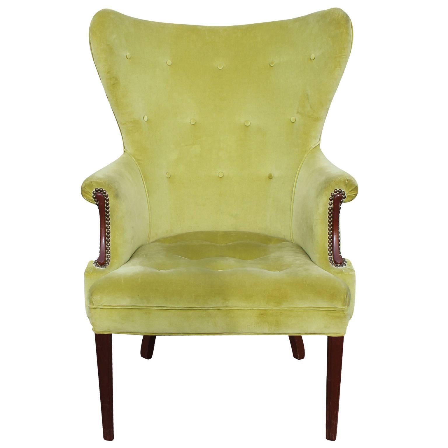 Striking pair of Mid-Century / Regency wingback chairs. Chairs have playful lines-ultra curvy and leggy. Brass tacks and walnut inserts adorn the arms. Chairs are upholstered in original chartreuse velvet which needs re upholstery.