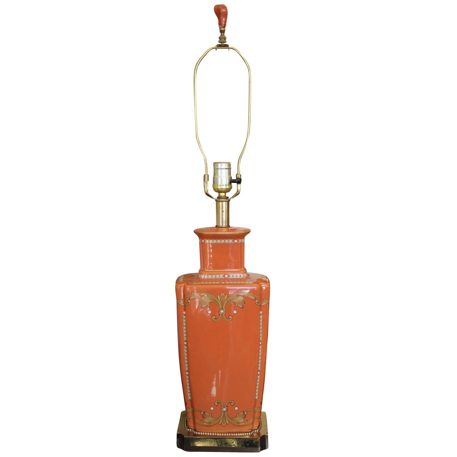 Glamorous pair of orange ceramic table lamps. Urn shaped lamps feature hand-painted scrollwork motifs. Shiny brass bases. Organic Amber stone finials complete the lamps.