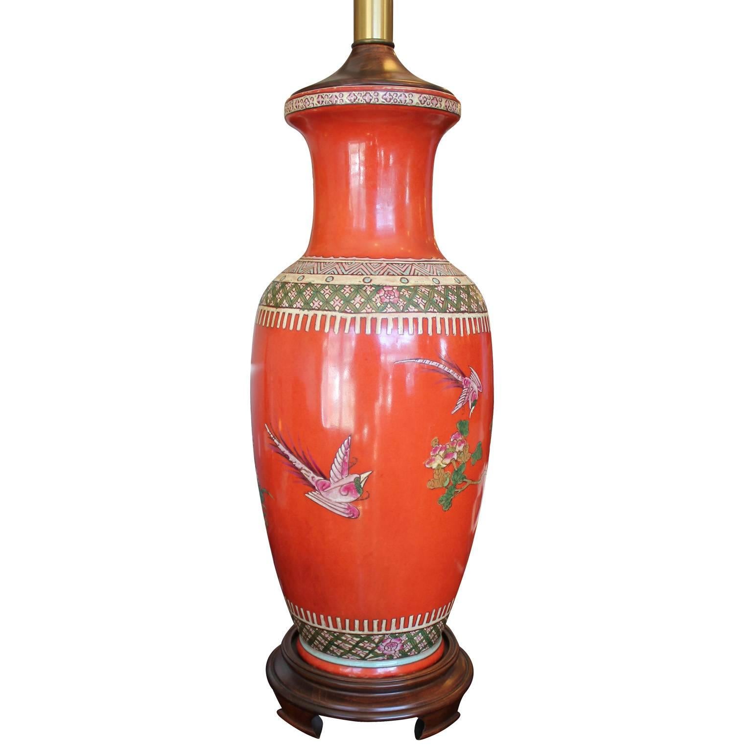 Beautiful pair of table lamps by Labarge. Lamps are in pumpkin orange with an intricate and colorful Asian motif featuring birds and flowers. Brass accents and ming bases finish of the lamps elegantly.