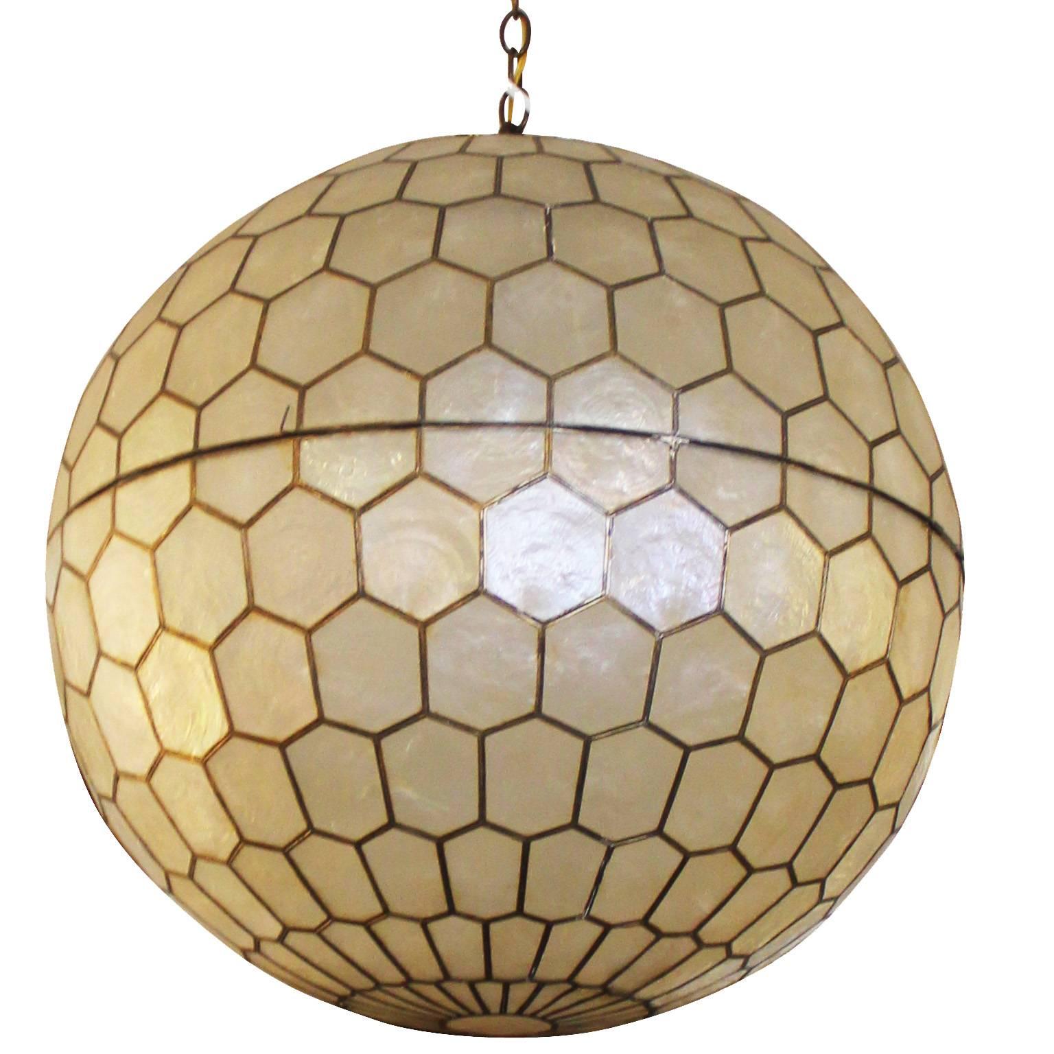 Architectural ball or globe chandelier by Feldman. Geometric panels of capiz shell fixed with brass give form to the piece. Fixture opens in the middle to access light bulb.