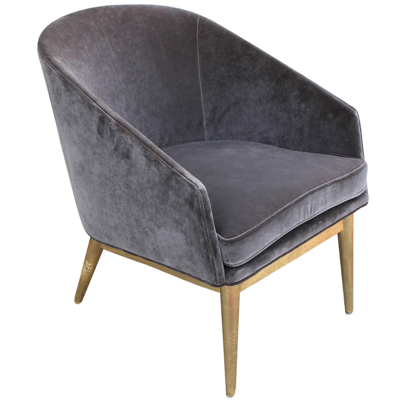 Striking pair of barrel back lounge chairs. Chairs are freshly upholstered in a luxe grey velvet. Bases are finished in gold leaf. These are a smaller scale- would be great for occasional seating or a bedroom. Stunning from every angle.
