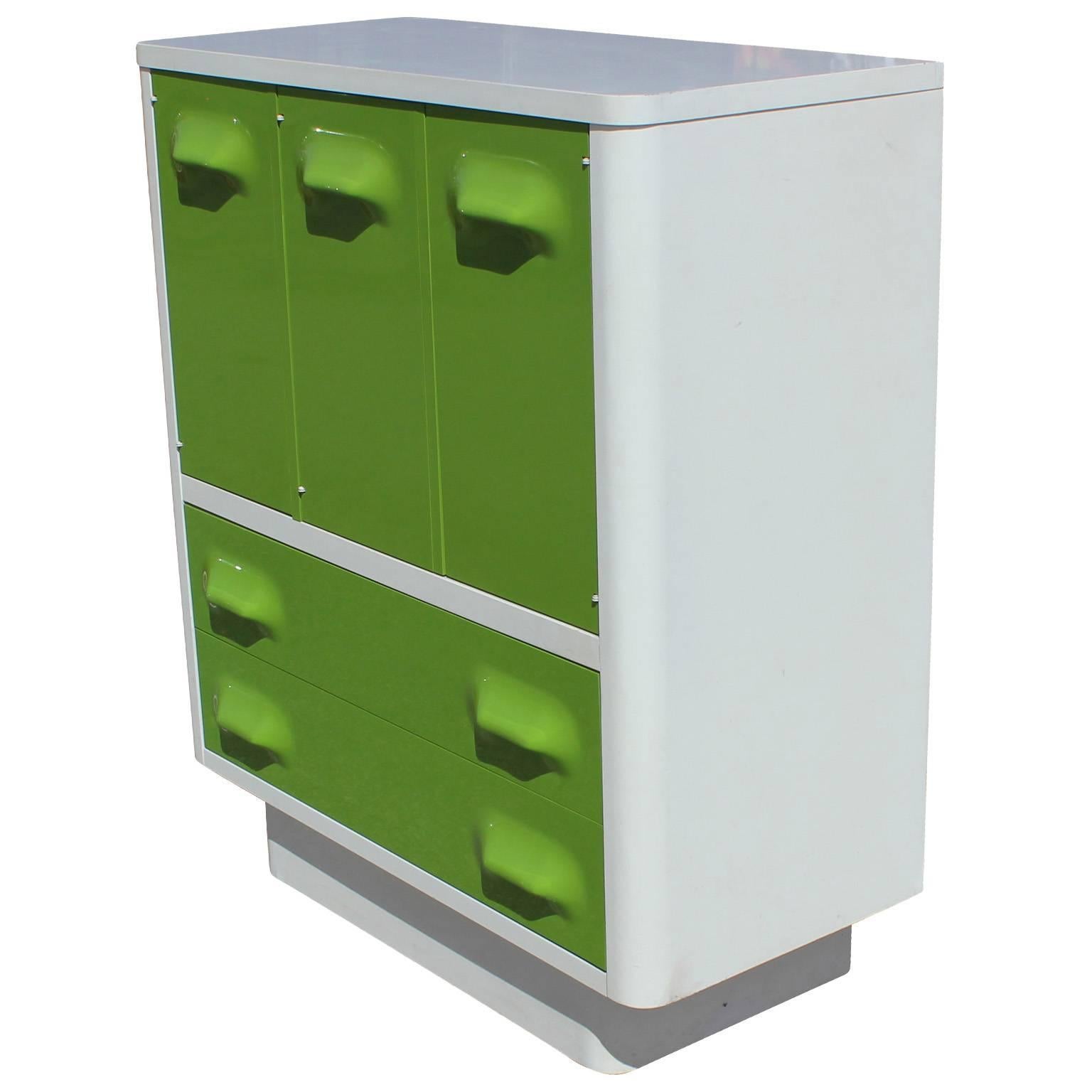 Chapter one Broyhill armoire or dresser in the style of Raymond Loewy's DF2000 line. Dresser is in white with lime green drawer fronts. Two large drawers. Left cabinet door opens to a single shelf. Middle and right door open to three pull out