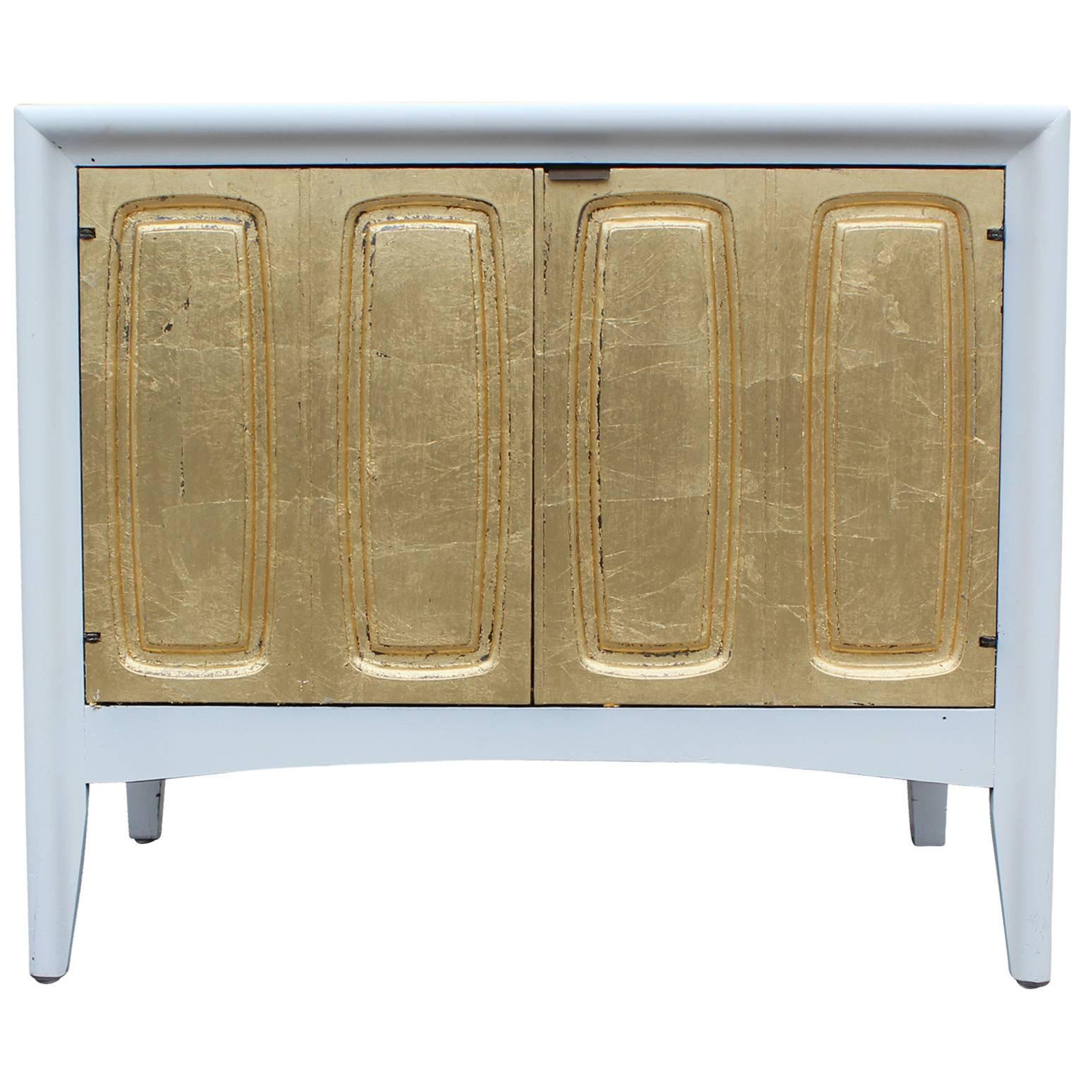 Dramatic pair of night stands or side tables. Cases are finished in a satiny white lacquer. Drawer fronts are covered in a textured gold leaf finish. Two doors open to cabinet space.
