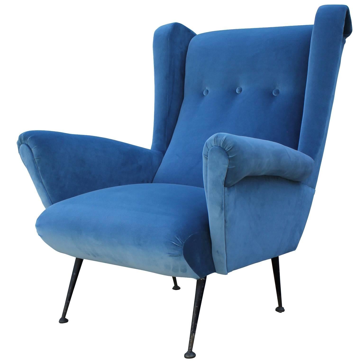 Wonderful pair of wingback lounge chairs made in Italy, circa 1950. Chairs are freshly upholstered in a soft blue velvet. Delicate black enameled legs are finished in patinated brass levelers. Stunning from all angles.