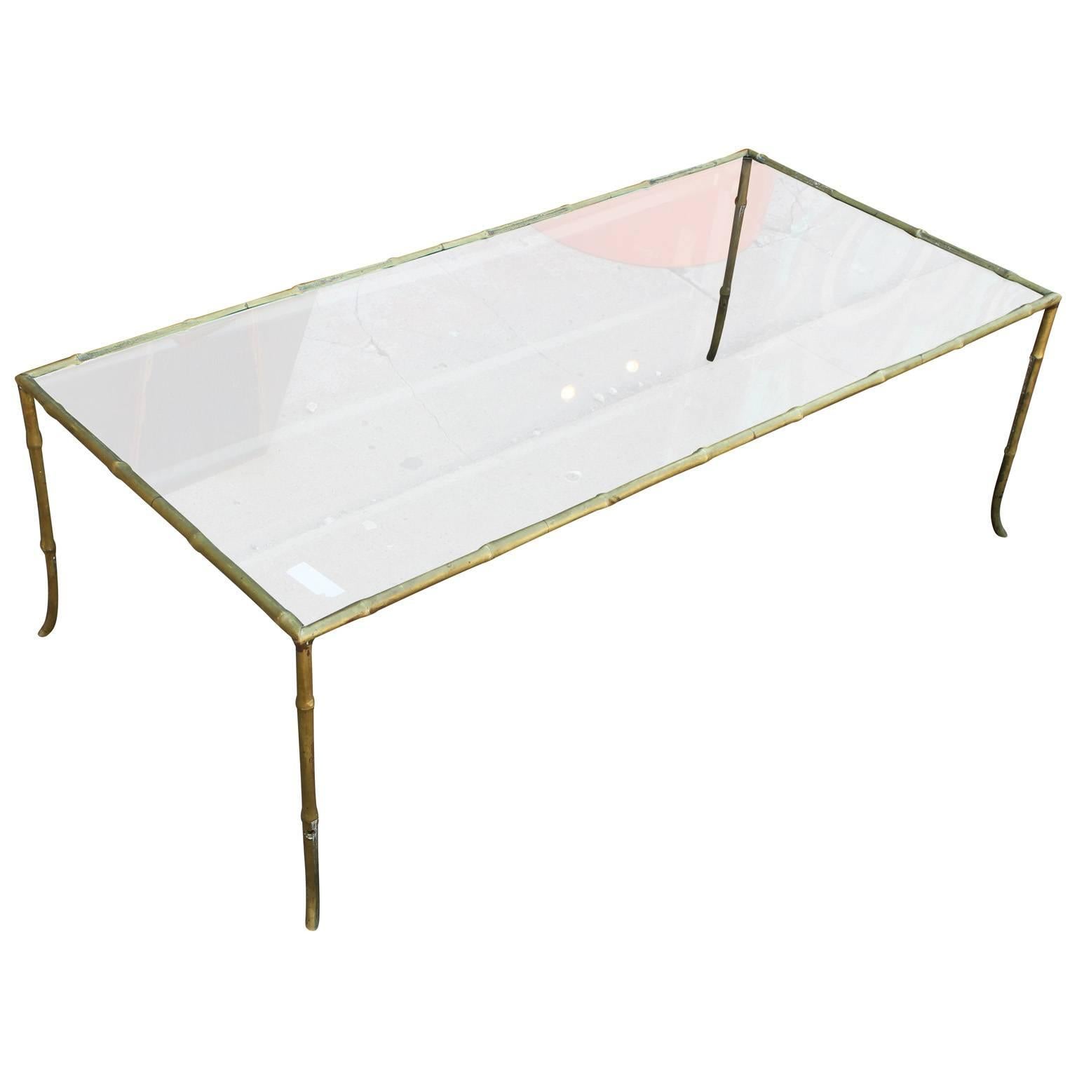 Elegant French brass and glass coffee table. Faux bamboo frame has simple delicate lines. Table is topped in glass. Perfect in a Mid-Century, tranistional, or Hollywood Regency interior. Possibly by Maison Bagues.