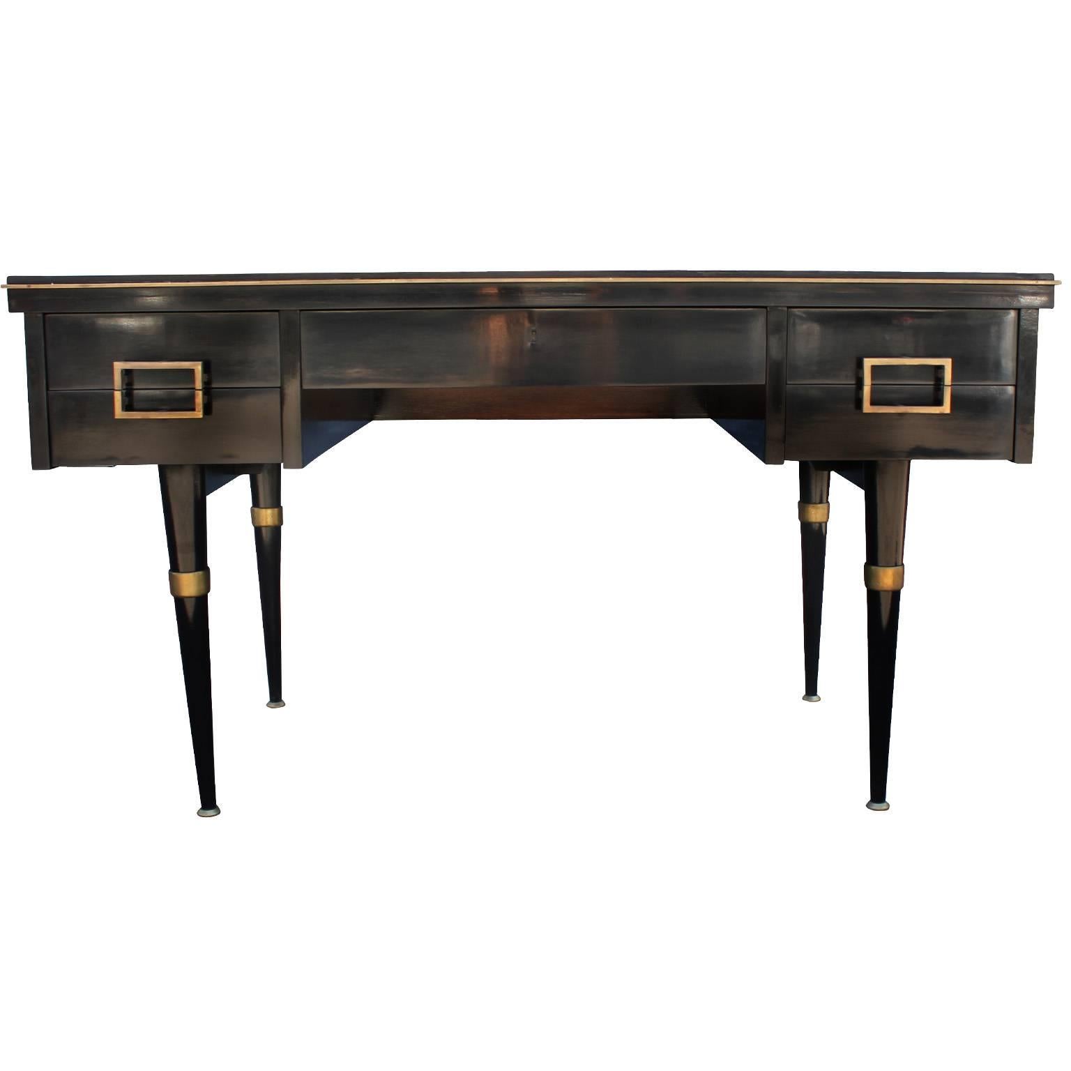 Dramatic Argentinean executive desk in glossy black lacquer. Desk is accented in brass hardware. Top has a jade green writing surface trimmed in gold. Blonde burl wood inset on the back of desk adds visual interest. Five drawers provide storage.