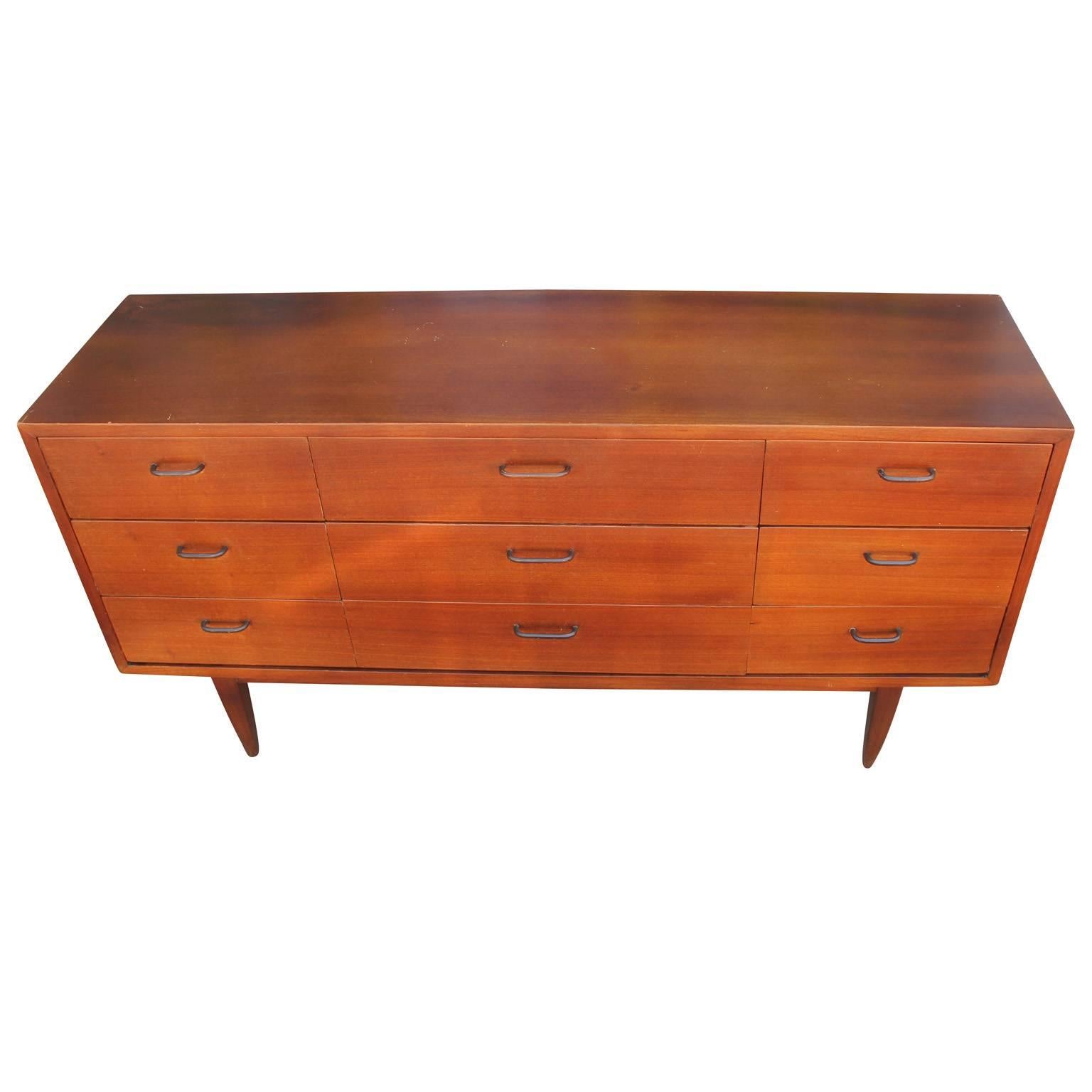 Wonderful nine-drawer teak dresser. Clean lined dresser is accented with heavily patinated brass pulls. Delicate tapered legs give the piece a light feel.