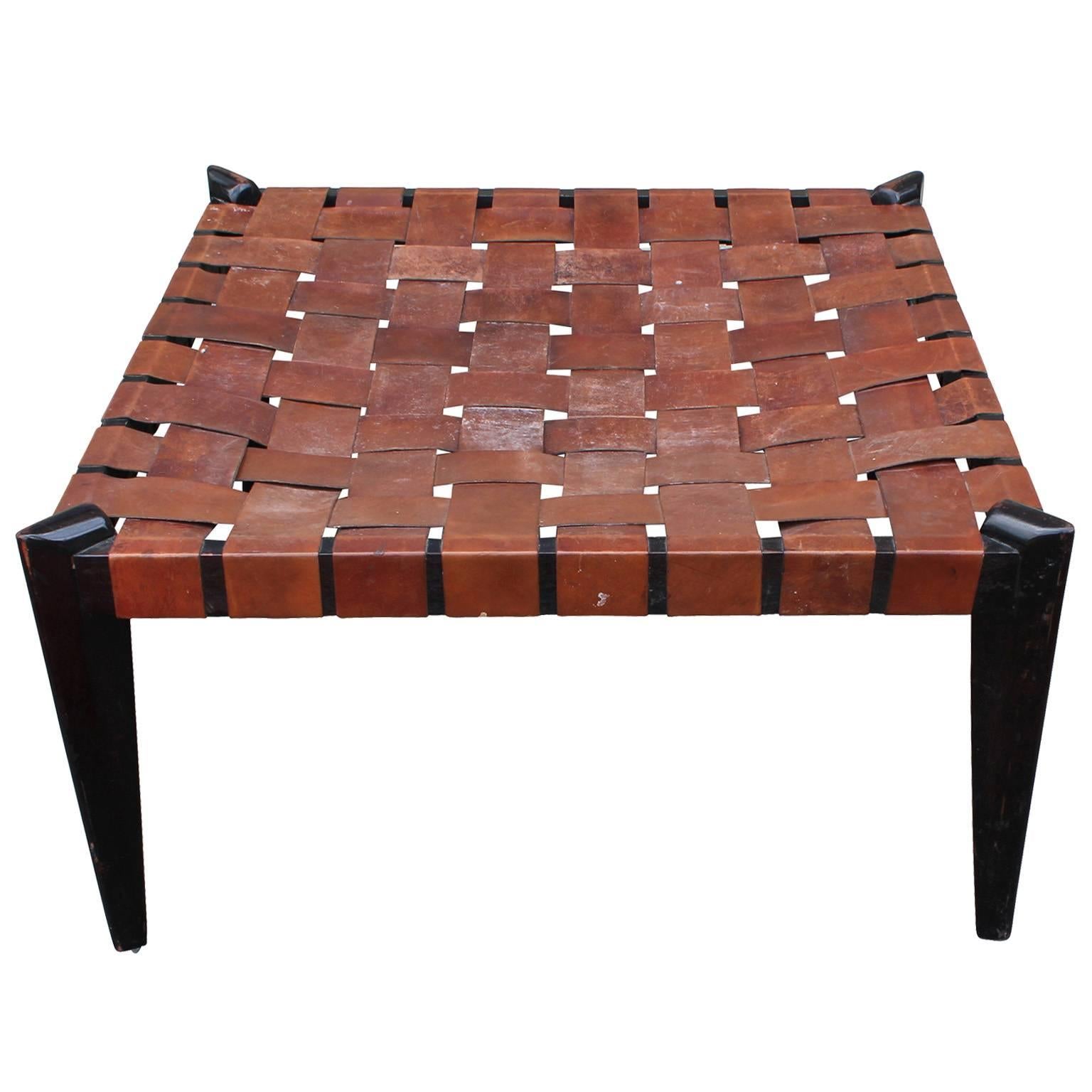 Fabulous ottoman, bench, or coffee table with a woven leather strap seat. Frame is finished in a dark almost ebony stain. Angular legs complete the piece. Perfect used as a coffee table or bench.