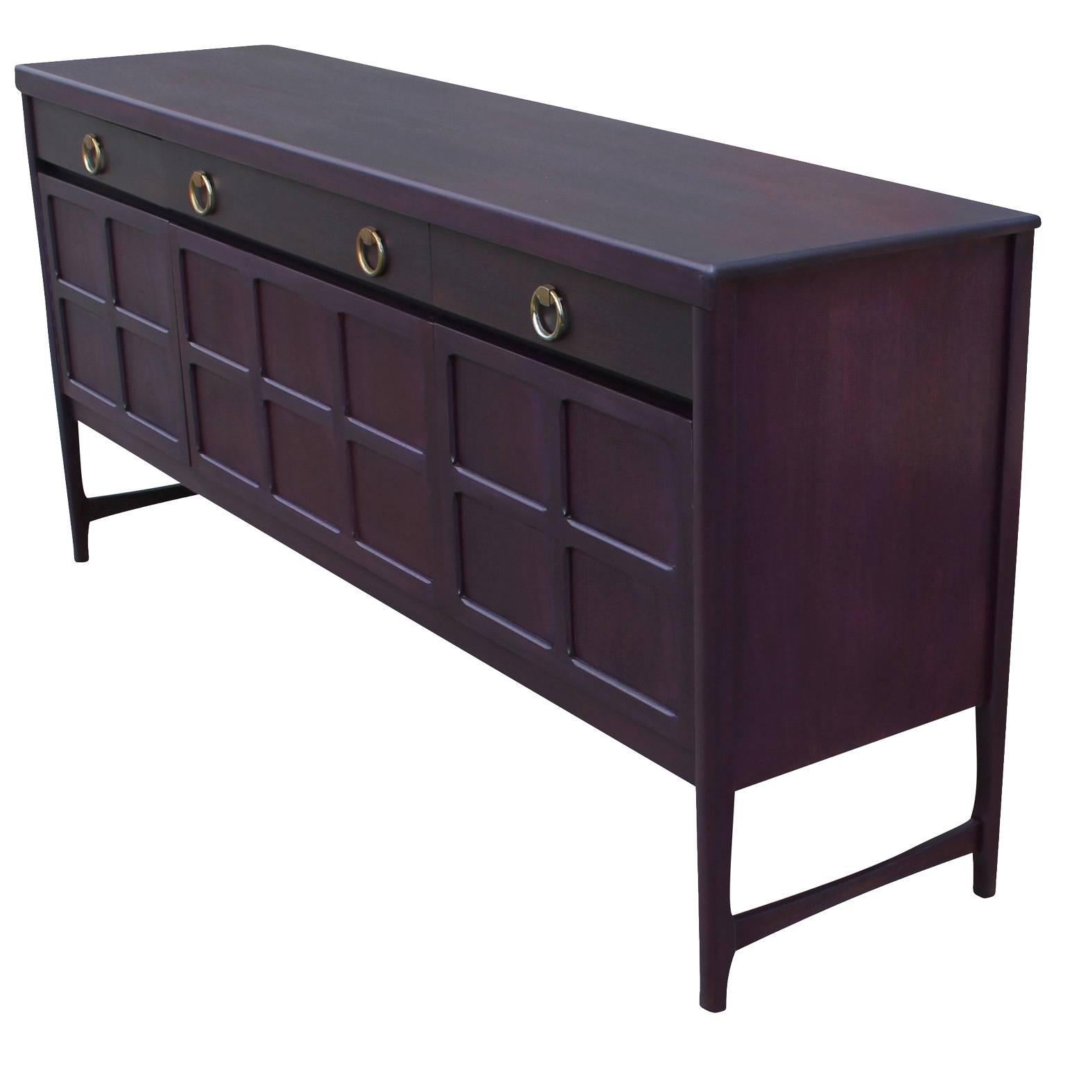 Wonderful sideboard or credenza finished in an eggplant purple aniline dye with brass ring pulls. Sideboard is constructed of mahogany and teak. Front middle cabinet door drops down to reveal a single shelf. Right and left cabinet doors open to a
