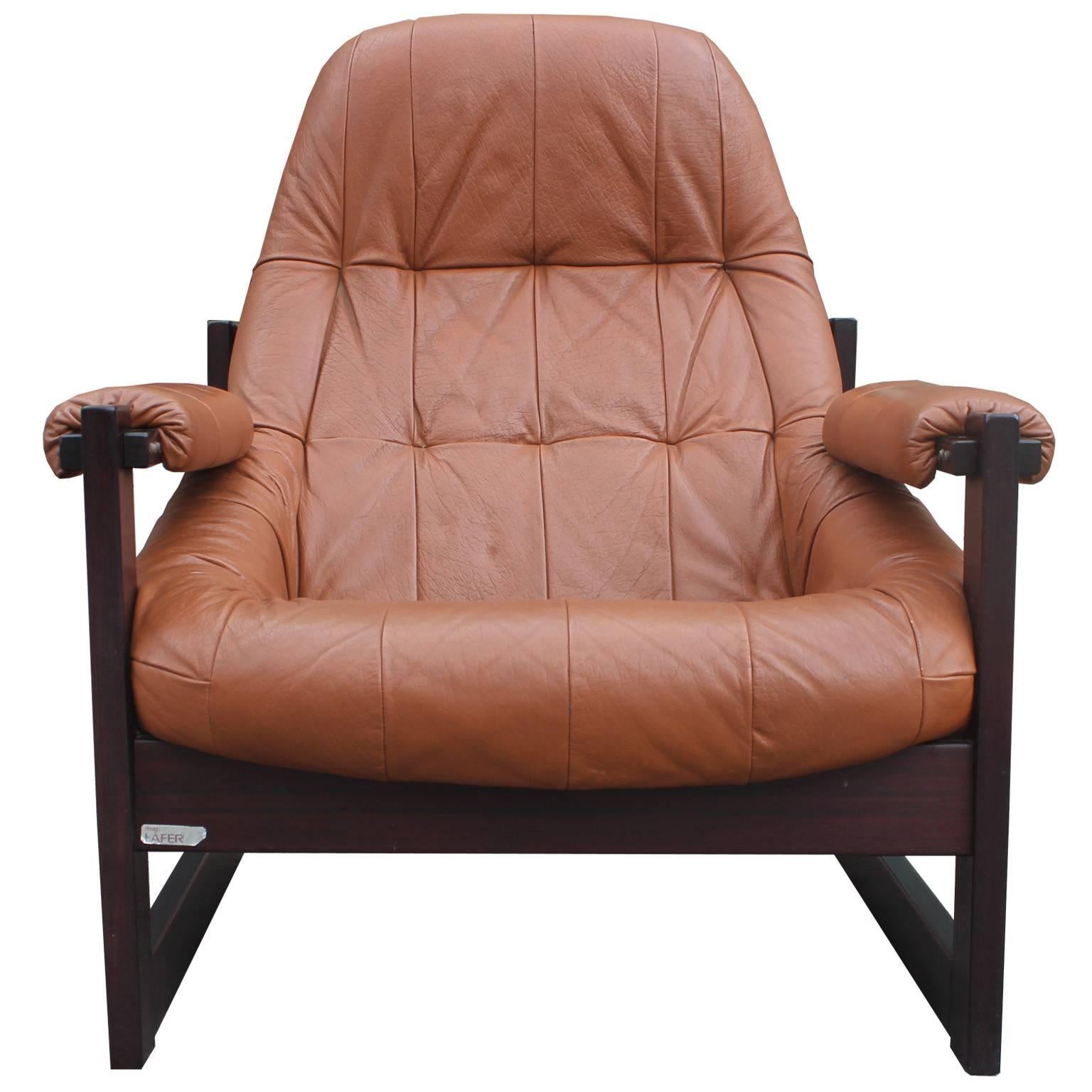 Incredible lounge chair and ottoman by Brazilian designer Percival Lafer. Ergonomic, organic shaped seat and ottoman are upholstered in original caramel brown leather. Frames are in Brazilian rosewood with shiny chrome accents. Original tags are