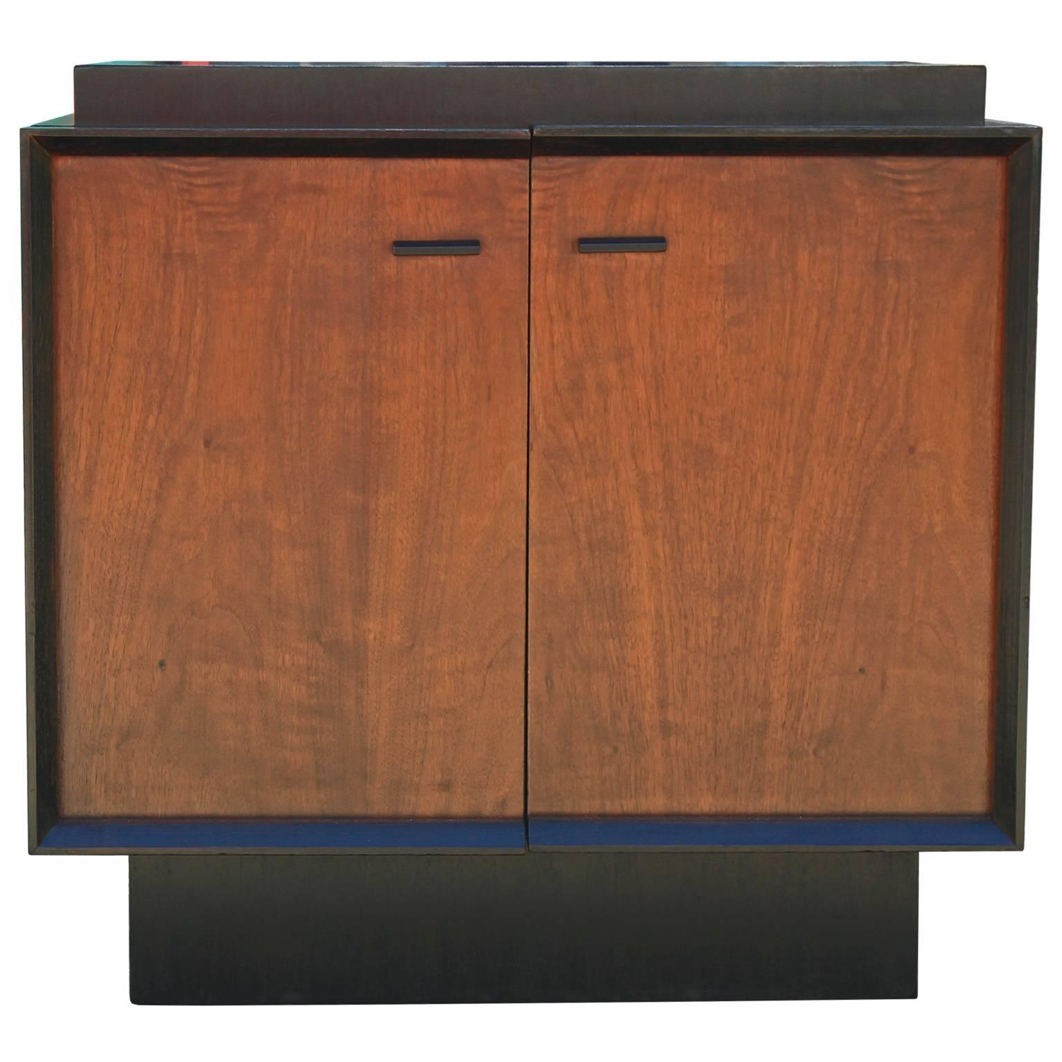 Sleek pair of clean lined bedside tables or small cabinets. Cabinets are nice vintage condition with ebonized cases and medium walnut doors. Doors open to a single shelf. Tables have wonderful, bold clean lines.