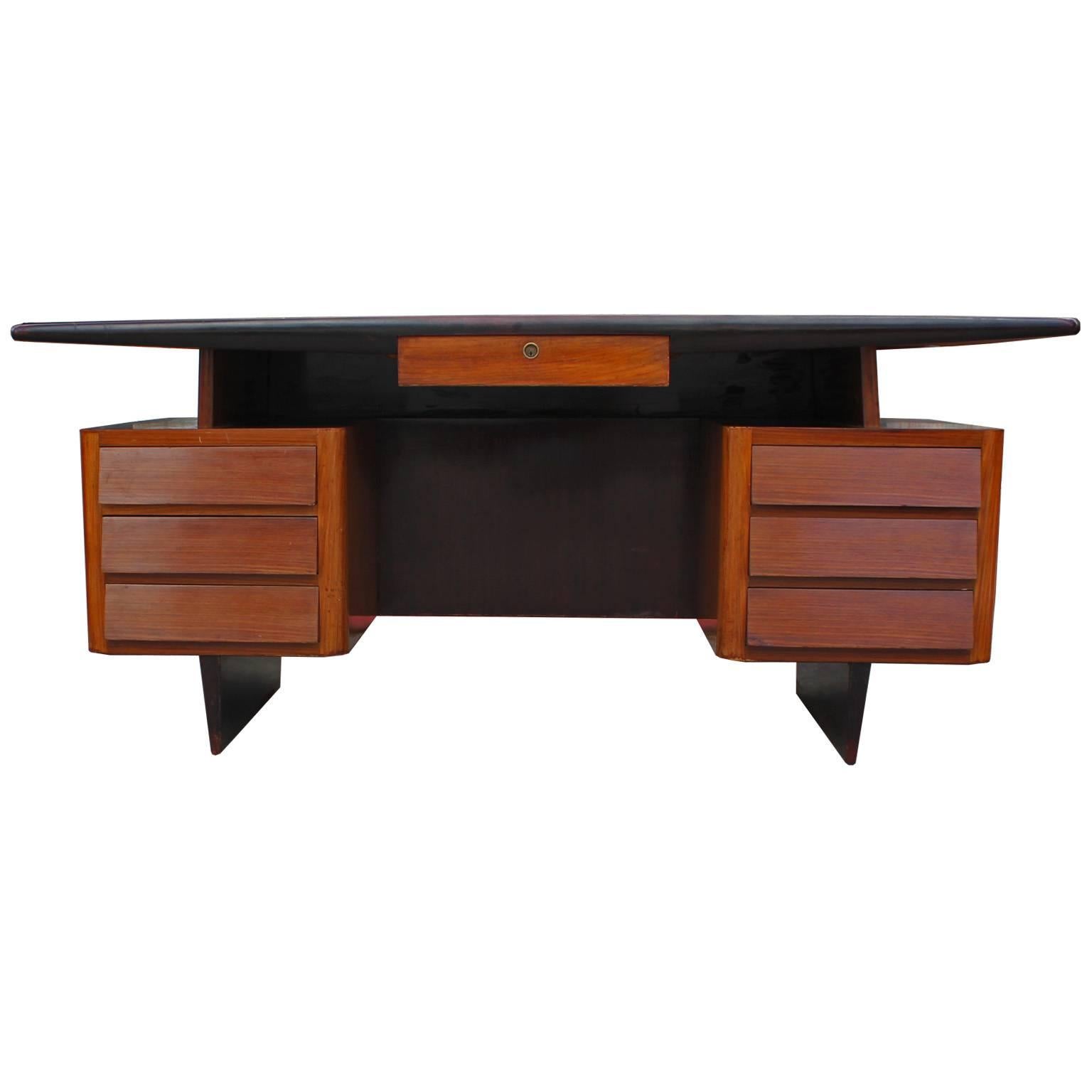 Fabulous executive desk in a two-tone finish. Sleek black glass desk top nicely contrasts the warm rosewood desk. Seven drawers provide excellent storage. Desk has excellent curved lines. Looks great from all angles. In nice vintage condition.