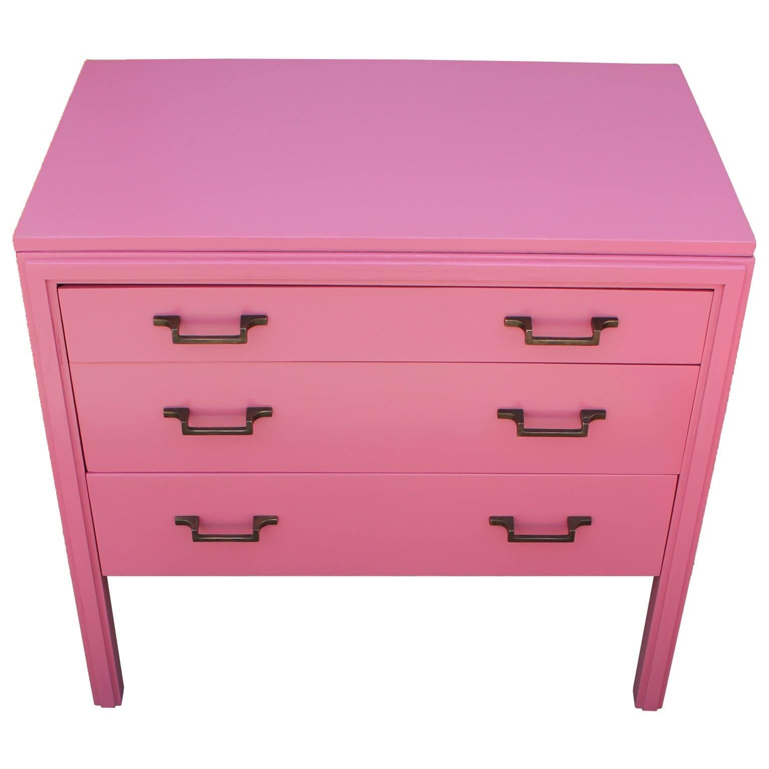 Sweet pair of bachelor's chest or night stands freshly lacquered in an ultra-smooth pink. Three drawers provide storage and long legs keep the pieces feeling light. Simple brass hardware with a heavy patina. Perfect pop of color to any space.