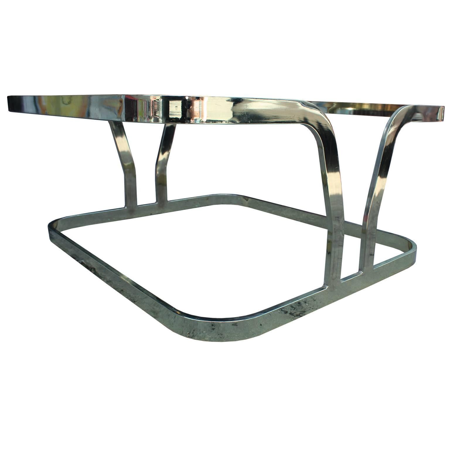 Excellent square coffee table. Sculptural flat bar brass base features a cantilevered shape. Topped with thick glass. Fabulous in a modern, Hollywood Regency, or Mid-Century space. Inquire for matching side tables and console.