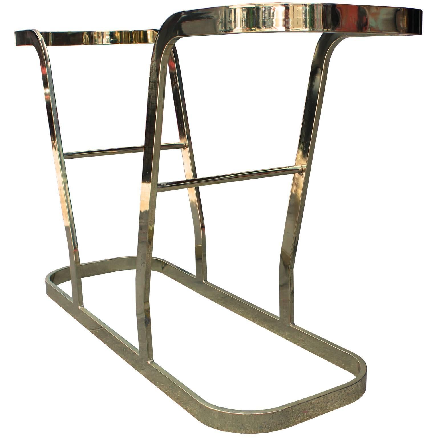 Sculptural console table. Sculptural flat bar brass base features a cantilevered shape. Topped with thick glass and a matching glass shelf. Fabulous in a modern, Hollywood Regency or Mid-Century space. Inquire for matching side tables and coffee