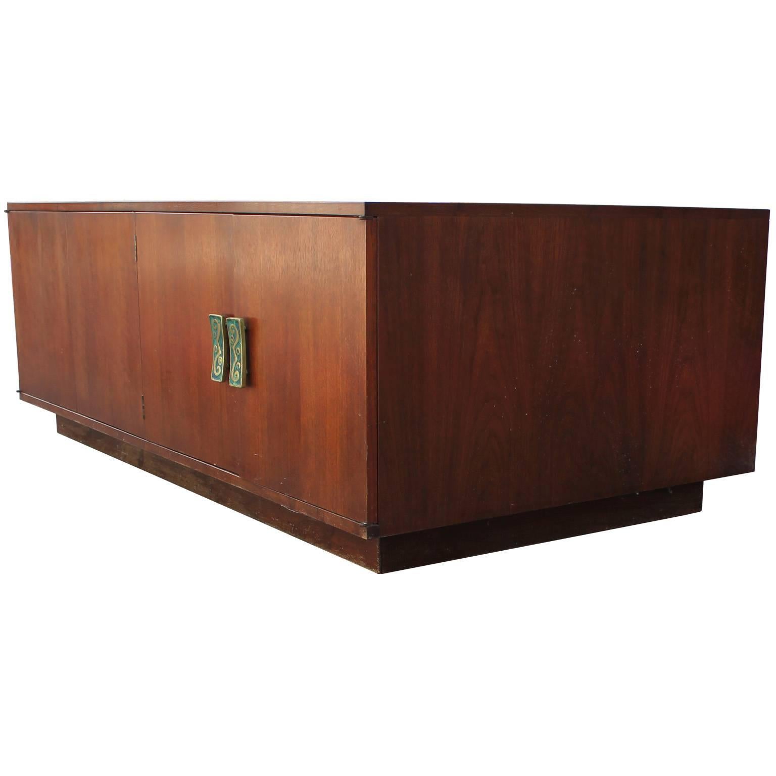 Clean lined Frank Kyle cabinet with handles designed by Frank Kyle and fabricated by Pepe Mendoza.  Handles are brass with teal swirl motifs in Kyle's iconic teal insert. The cabinet's simple lines let the beautiful hardware take center stage.