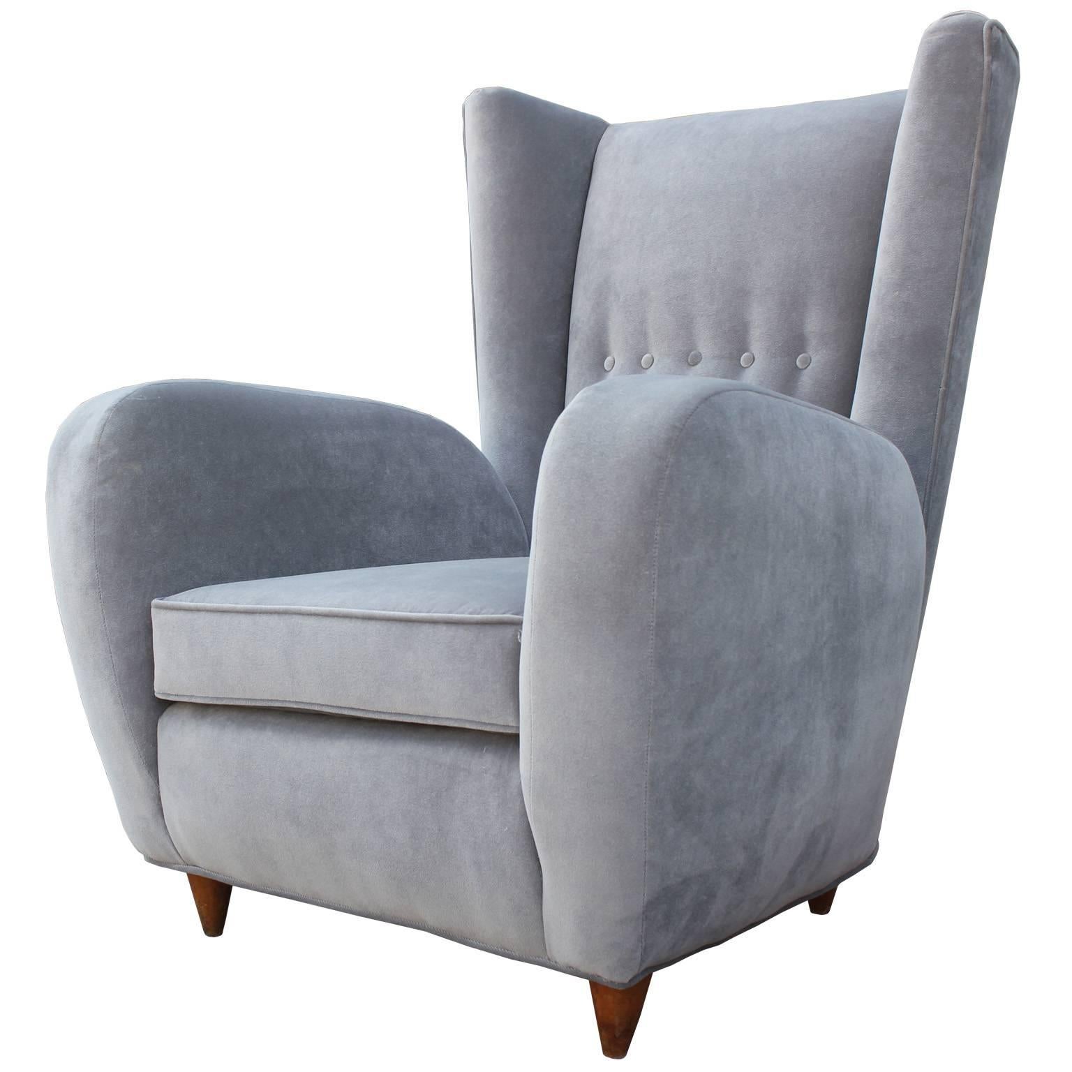 Pair of sculptural, Italian wingback lounge chairs in the style of Paolo Buffa. Chairs have dramatic over the top lines. Chairs are finished with delicate tapered legs. Freshly upholstered in a pale silver grey velvet.