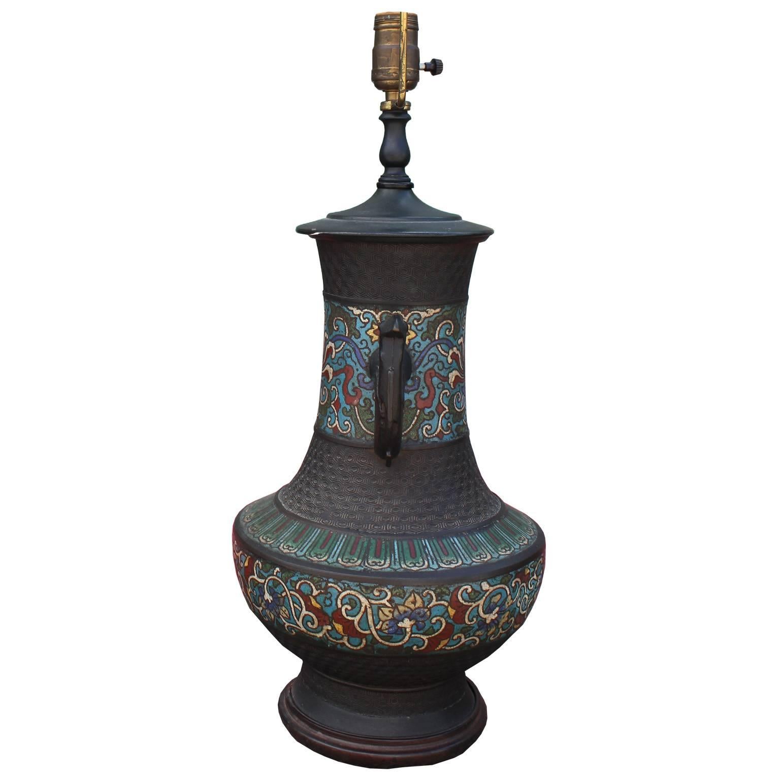 Striking Chinese Champlevé Cloisonné table lamp. Urn shaped bronze table lamp is enameled with a floral motif in turquoise, red, green, blue, and white. Figural handles and textured bronze finish the piece. Excellent craftsmanship.