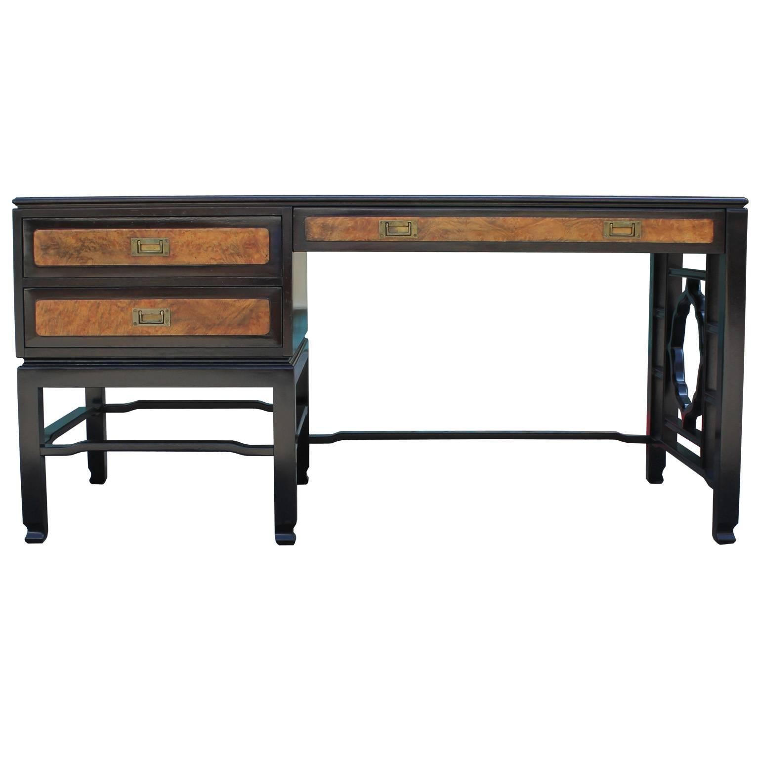 Excellent desk designed by John Widdicomb. Desk has wonderful lines with a beautiful trellis work leg. Desk is freshly finished in an ebony base and deep walnut body which nicely contrasts the burl wood accents. Brass campaign style hardware finish