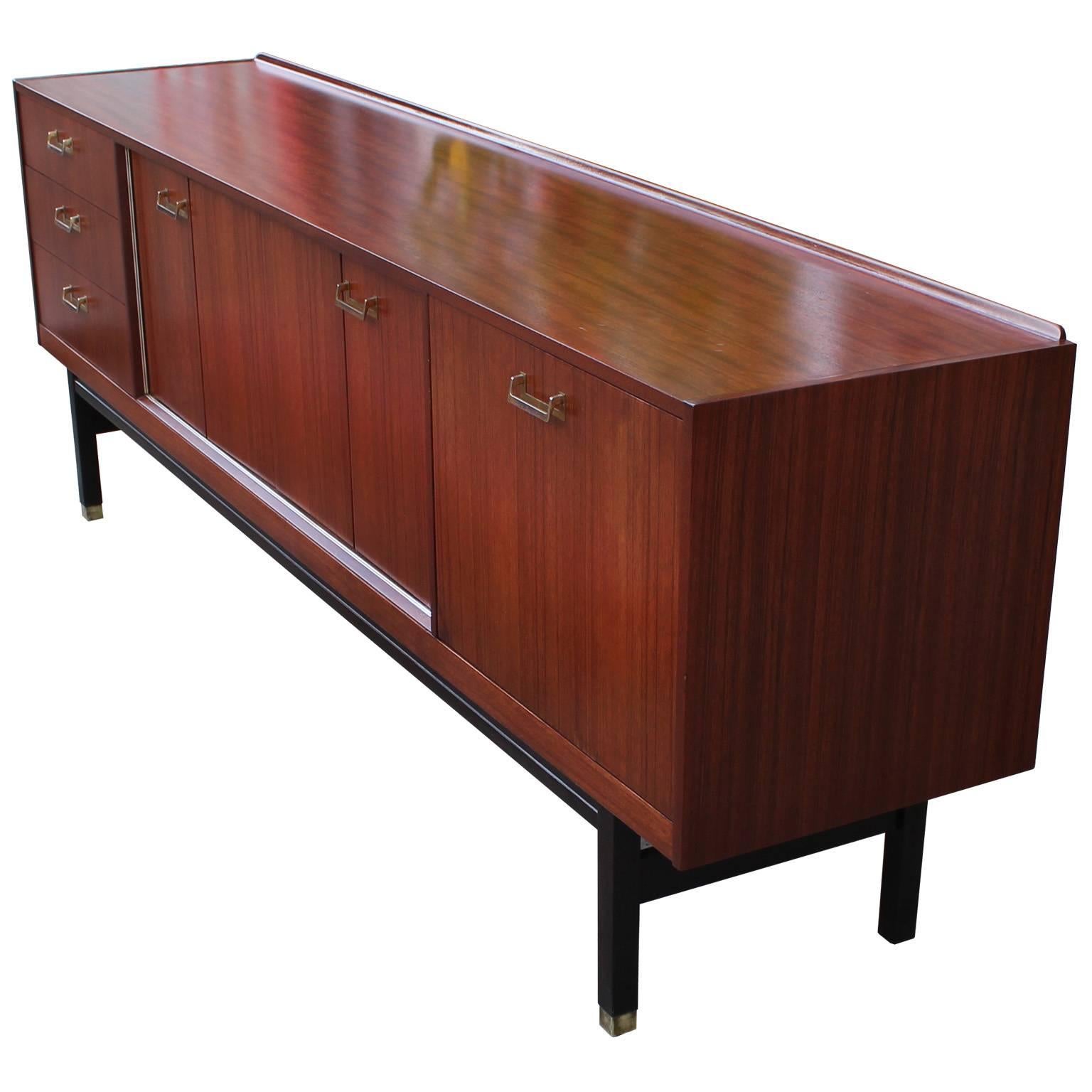 Sleek sideboard or credenza. Sideboard features beautiful grained wood veneer. Two bi-fold doors open to sectioned cabinet space. Laminate lined drop down door reveals open cabinet space. Three drawers provide additional storage. Rests upon a black