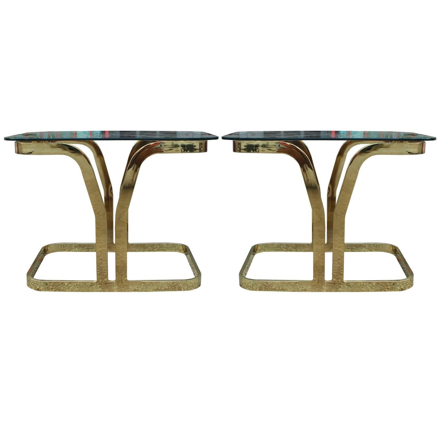 Excellent pair of cantilevered side or end tables. Sculptural brass bases have excellent lines. Topped with half inch thick glass. In the style of Karl Springer or Pace Collection. In nice vintage condition.