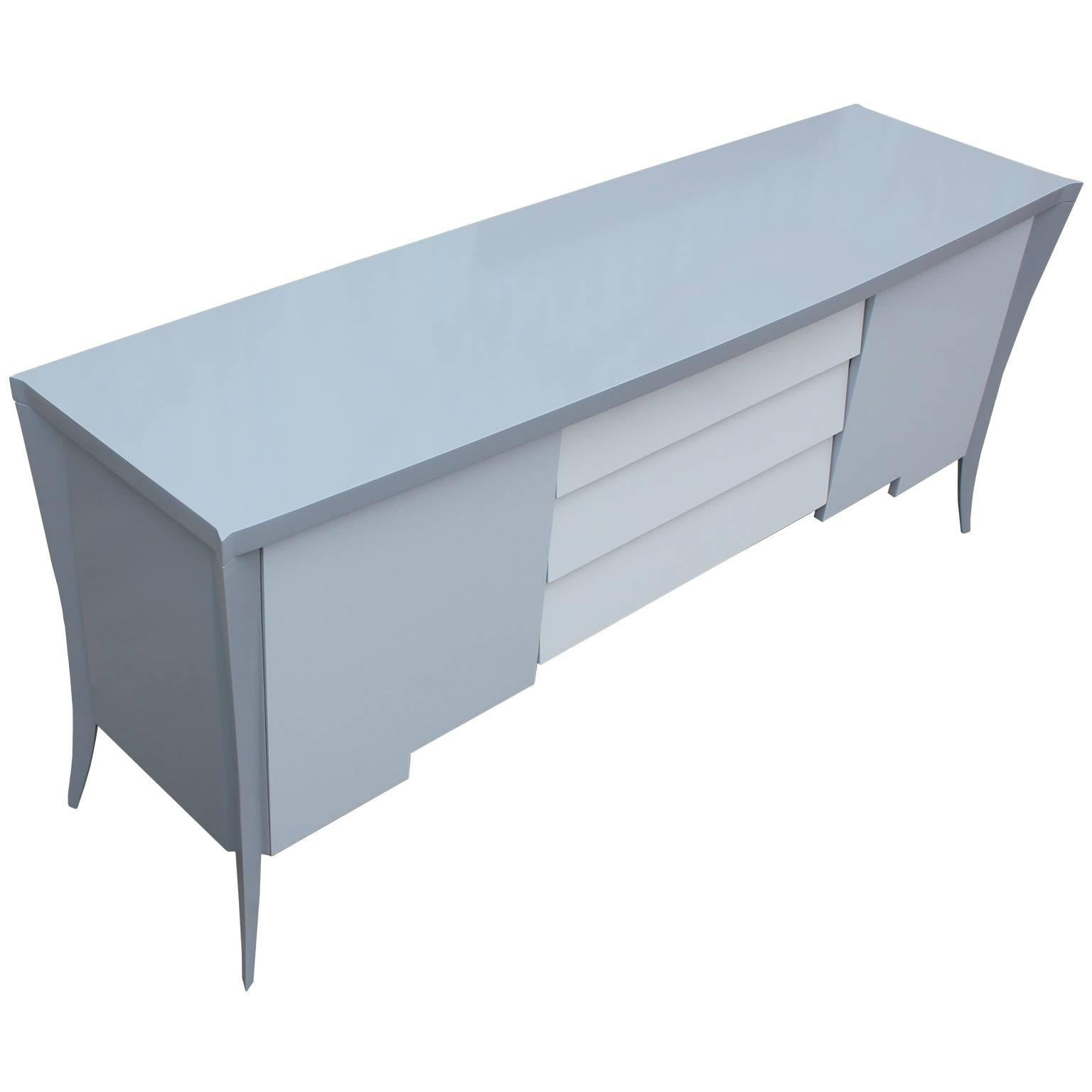 Fabulous, sculptural sideboard or credenza. Sideboard is freshly refinished in an incredibly smooth lacquer in three shades of grey. Cabinet doors on either side open to a single shelf. Three pull out drawers provide additional storage. Stunning