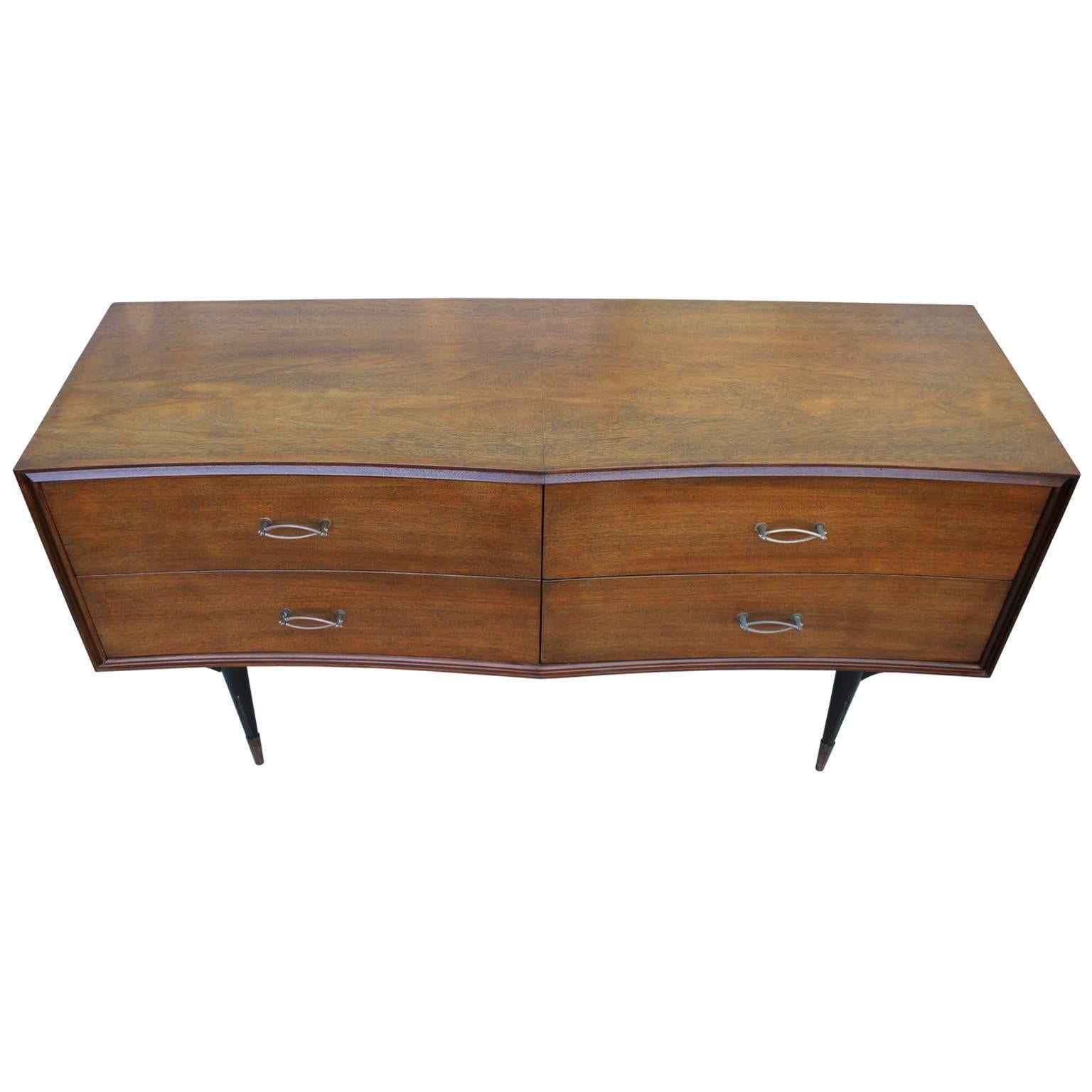 Sculptural Italian dresser. Dresser has stunning lines with a double bowed in front and delicate tapered legs. Finished in a medium walnut. Lovely twisted hardware and accents finishes off the chest nicely. Excellent in a Mid-Century, Hollywood