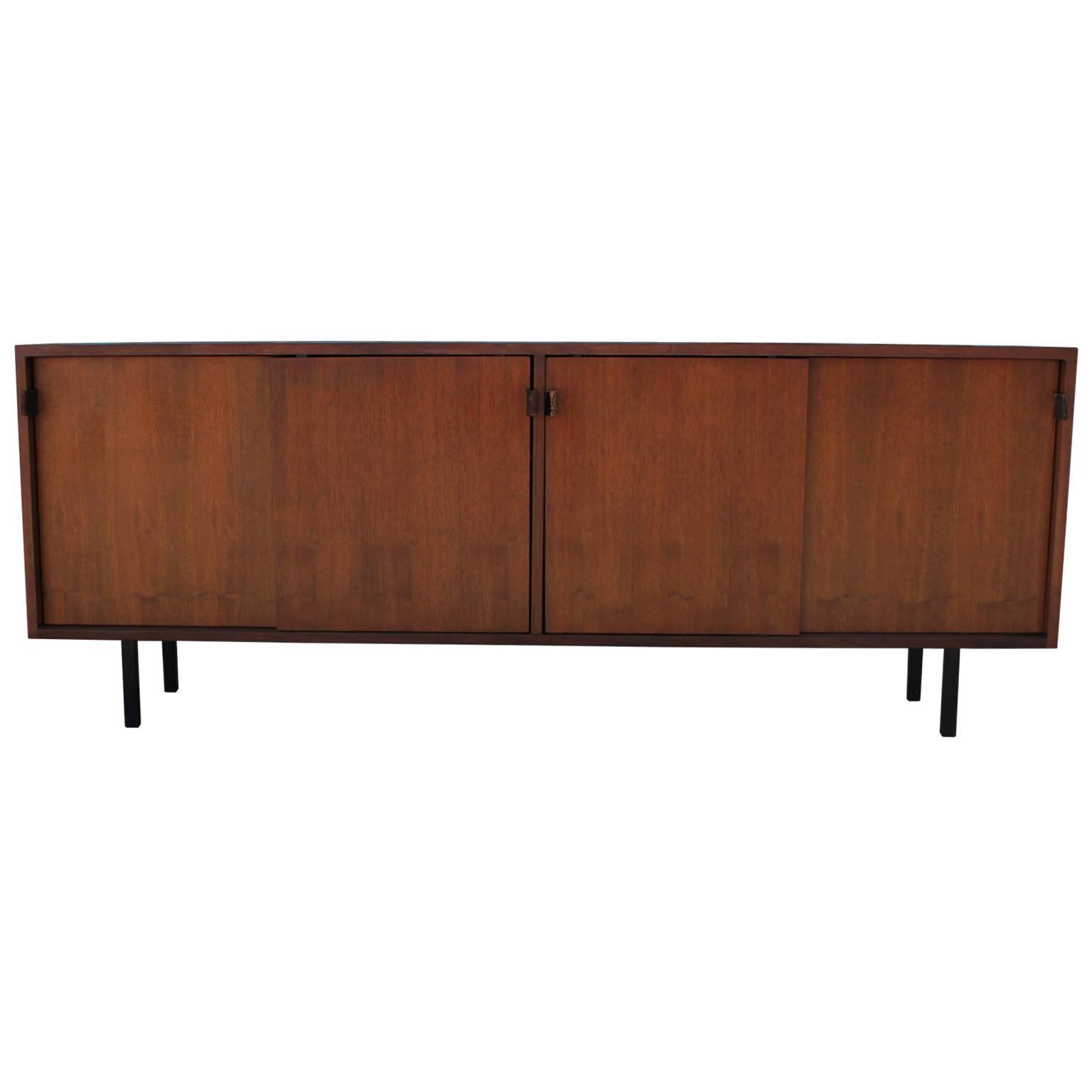 Beautiful sliding door credenza or sideboard by Knoll. Walnut has beautiful graining. Leather tab pulls have the perfect patina. Sliding doors open to reveal two shelves. Clean lined piece would look perfect in a modern, Mid-Century, Minimalist, or