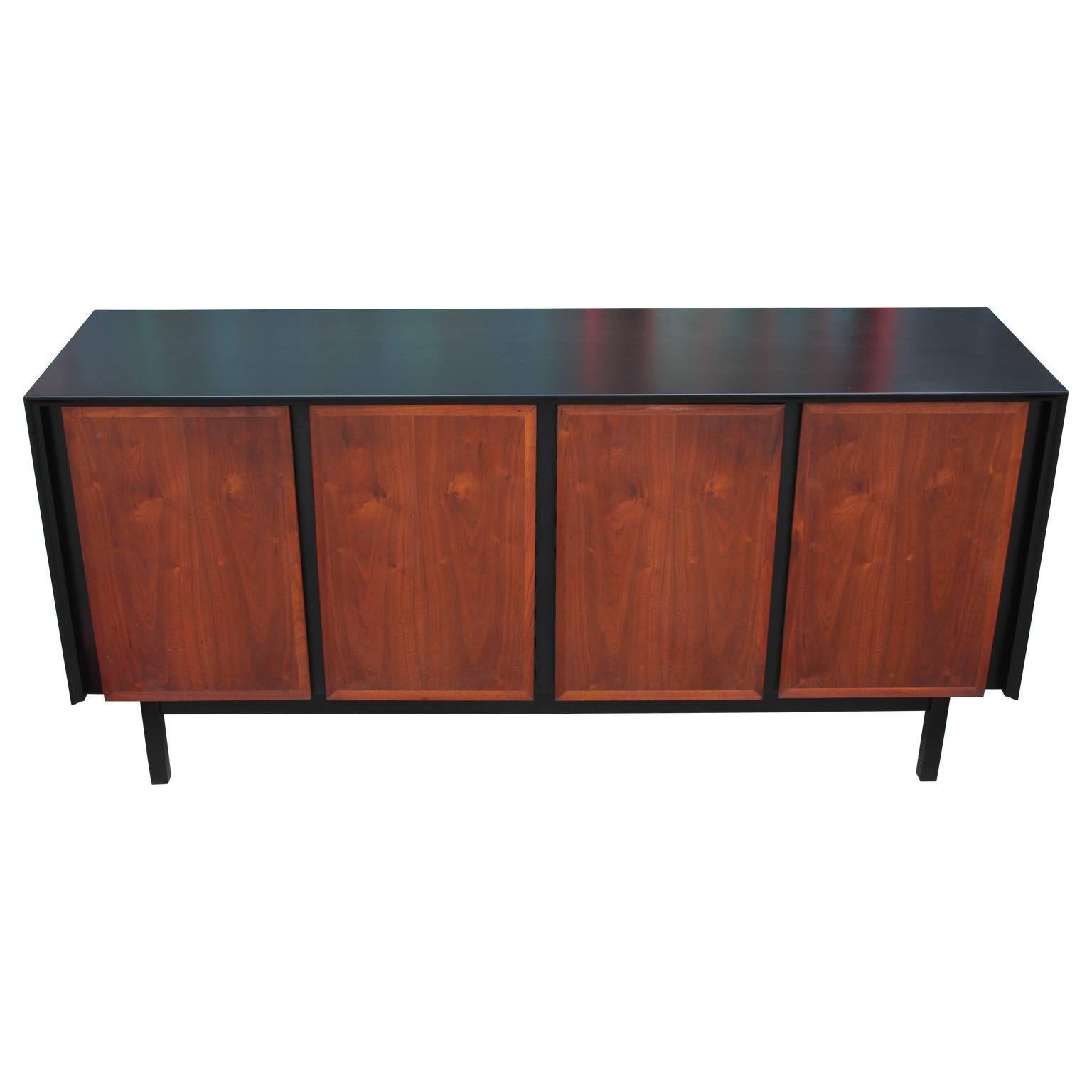 Sleek Mid-Century sideboard or credenza. Sideboard is freshly refinished with an ebonized case and walnut door fronts. Two doors open to three white drawers while the other two doors open to a single shelf.