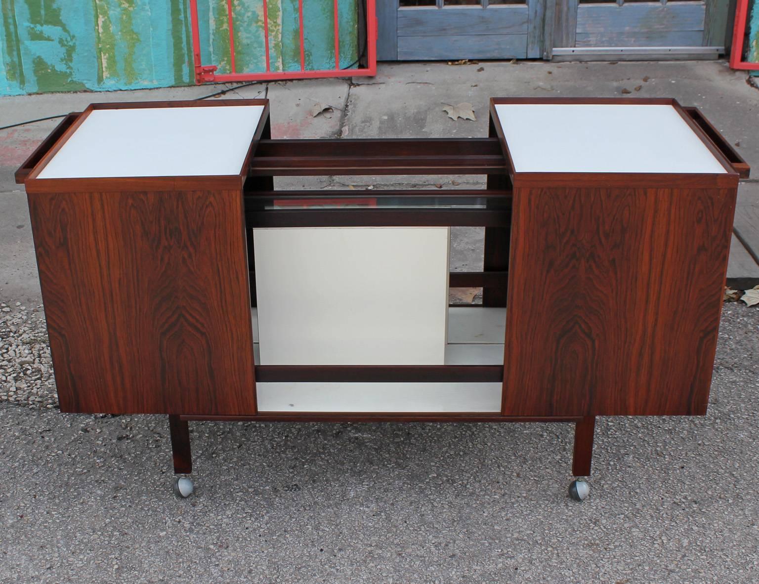 Lovely rosewood bar cart, opens to revel storage space, white laminate top. Stamped on bottom 
