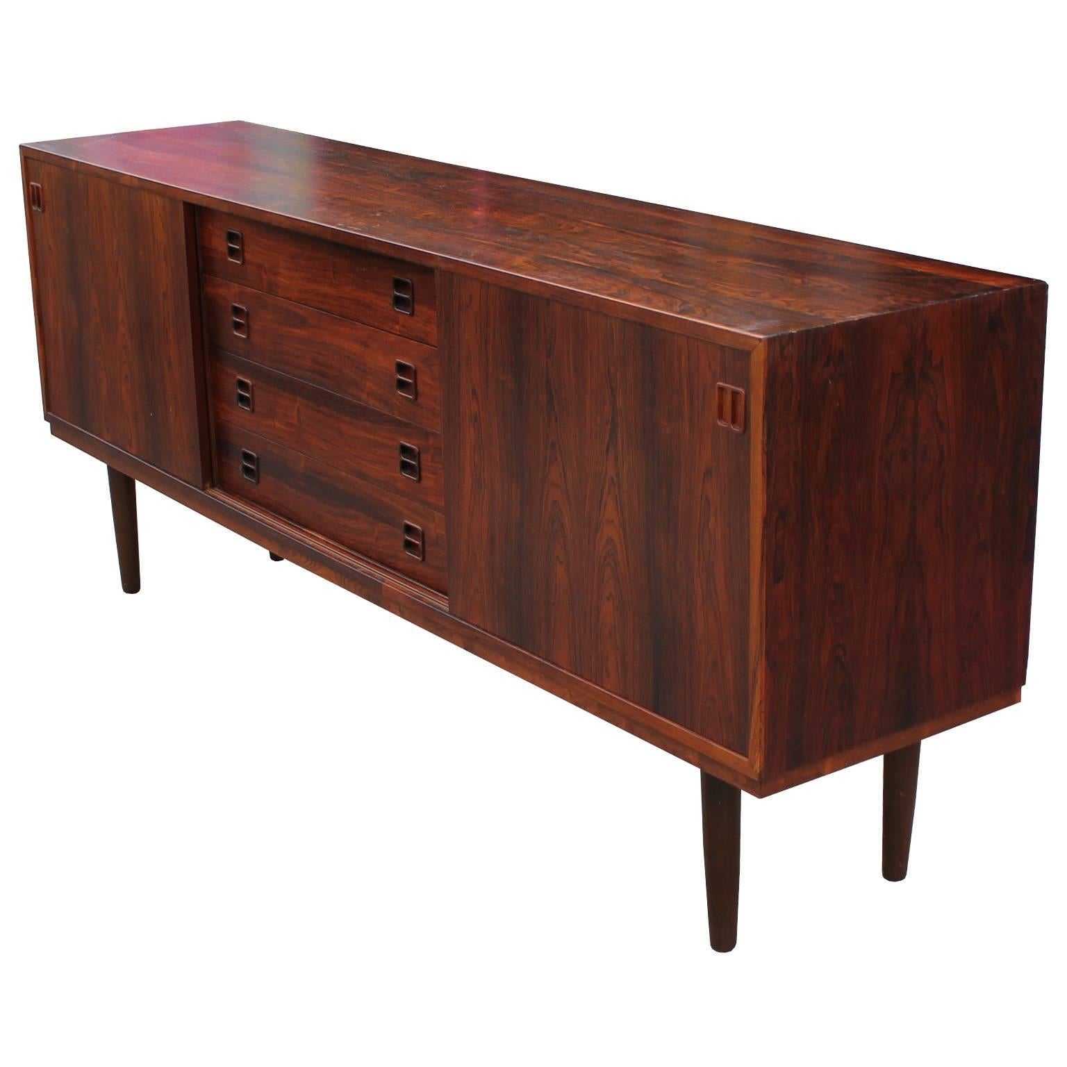 Great Brazilian rosewood sliding door sideboard or credenza. This wonderful sideboard has four drawers in the middle with two sliding doors on either side. This sideboard is in nice vintage condition with no major flaws to note. Attributed to Arne