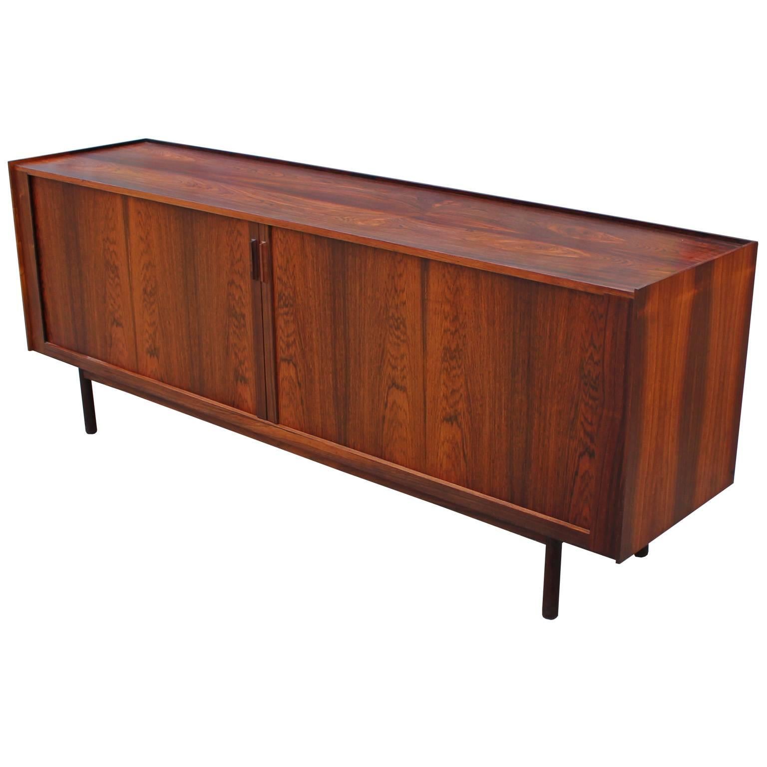 Wonderful Ib Kofod-Larsen tambour door rosewood sideboard or credenza from Denmark. The simple design along with excellent quality makes this sideboard a true masterpiece. The matched Brazilian rosewood will turn heads in any room. In great vintage